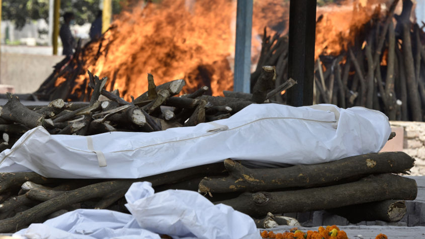 The body of a person who died of COVID-19 is placed on a pyre while others burn in the background at Sector 94, on April 21, 2021 in Noida, India.