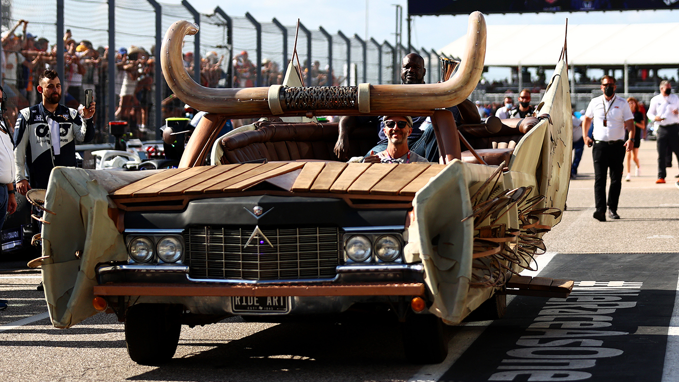 Shaquille O'Neal delivers the trophy to the podium at the United States Grand Prix.
