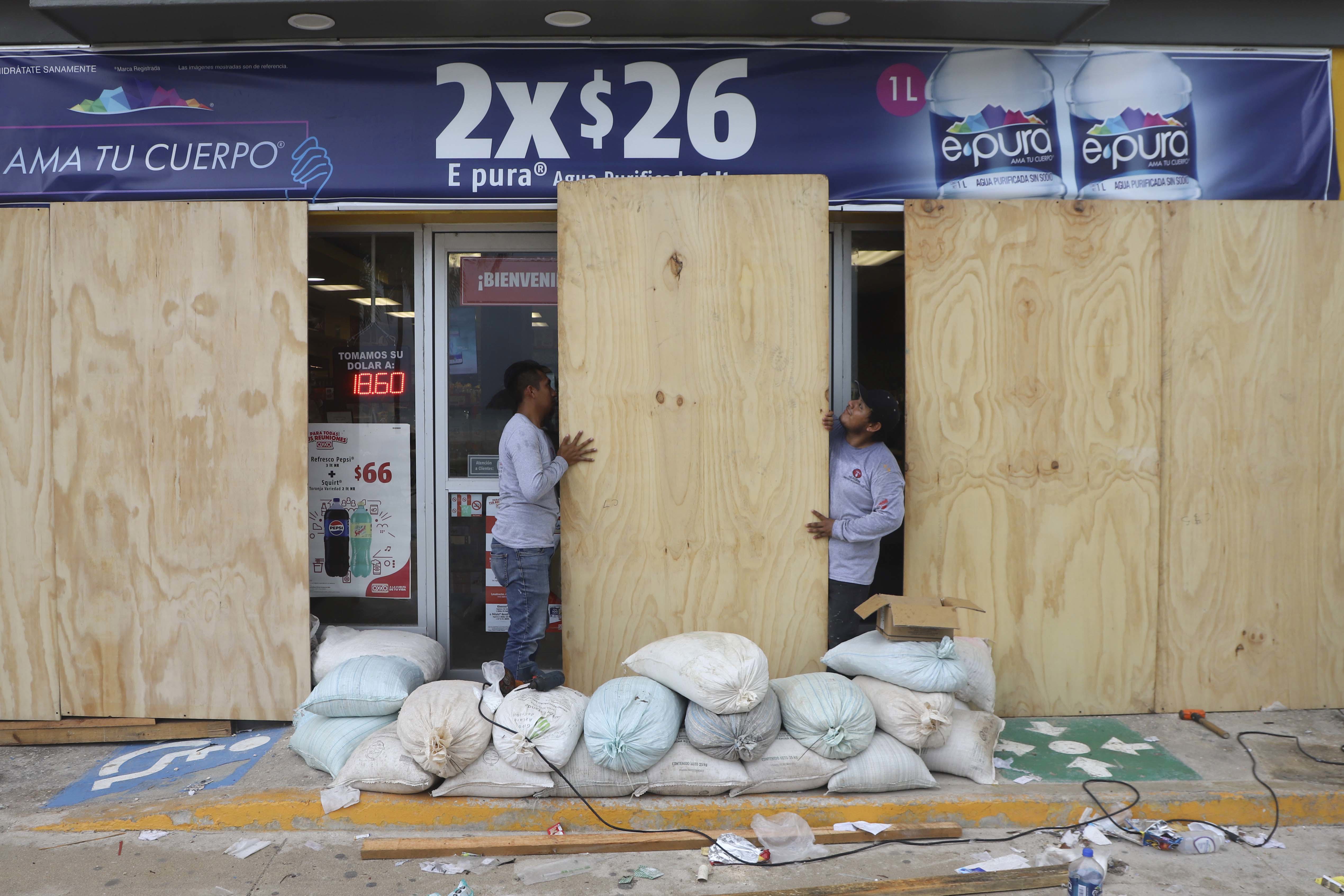 Trabajadores tapan una tienda de comestibles para protegerla del huracán Milton, en Progreso, estado de Yucatán, México.