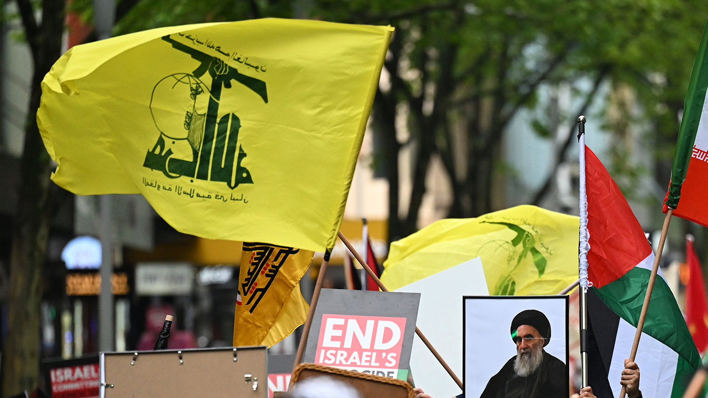 Protesters carry the yellow flag of Hezbollah and images of the militant group's late leader Hassan Nasrallah.