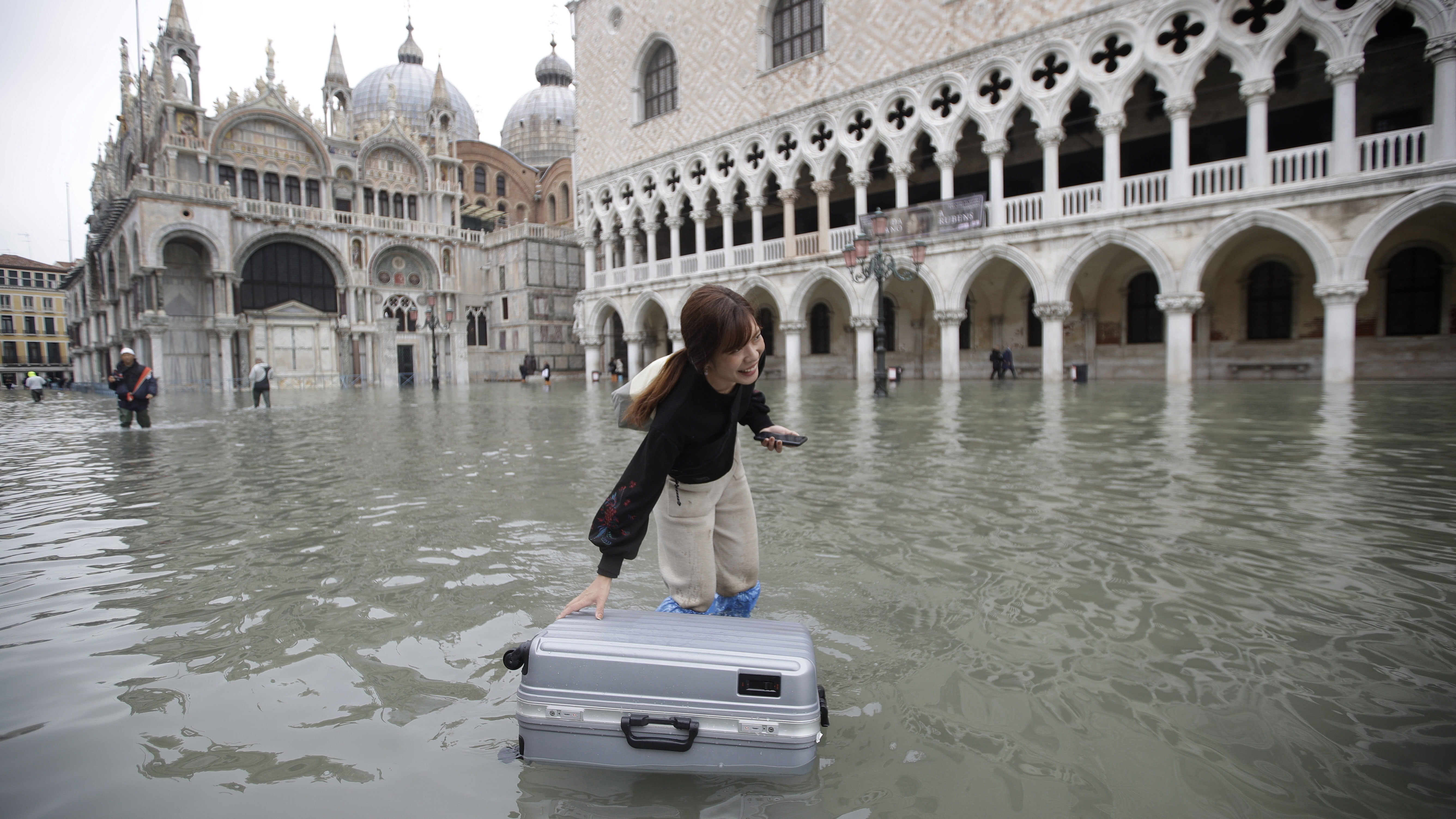 A tourist pushes her floating luggage in an inundated St. Mark's Square during the floods of 2019.