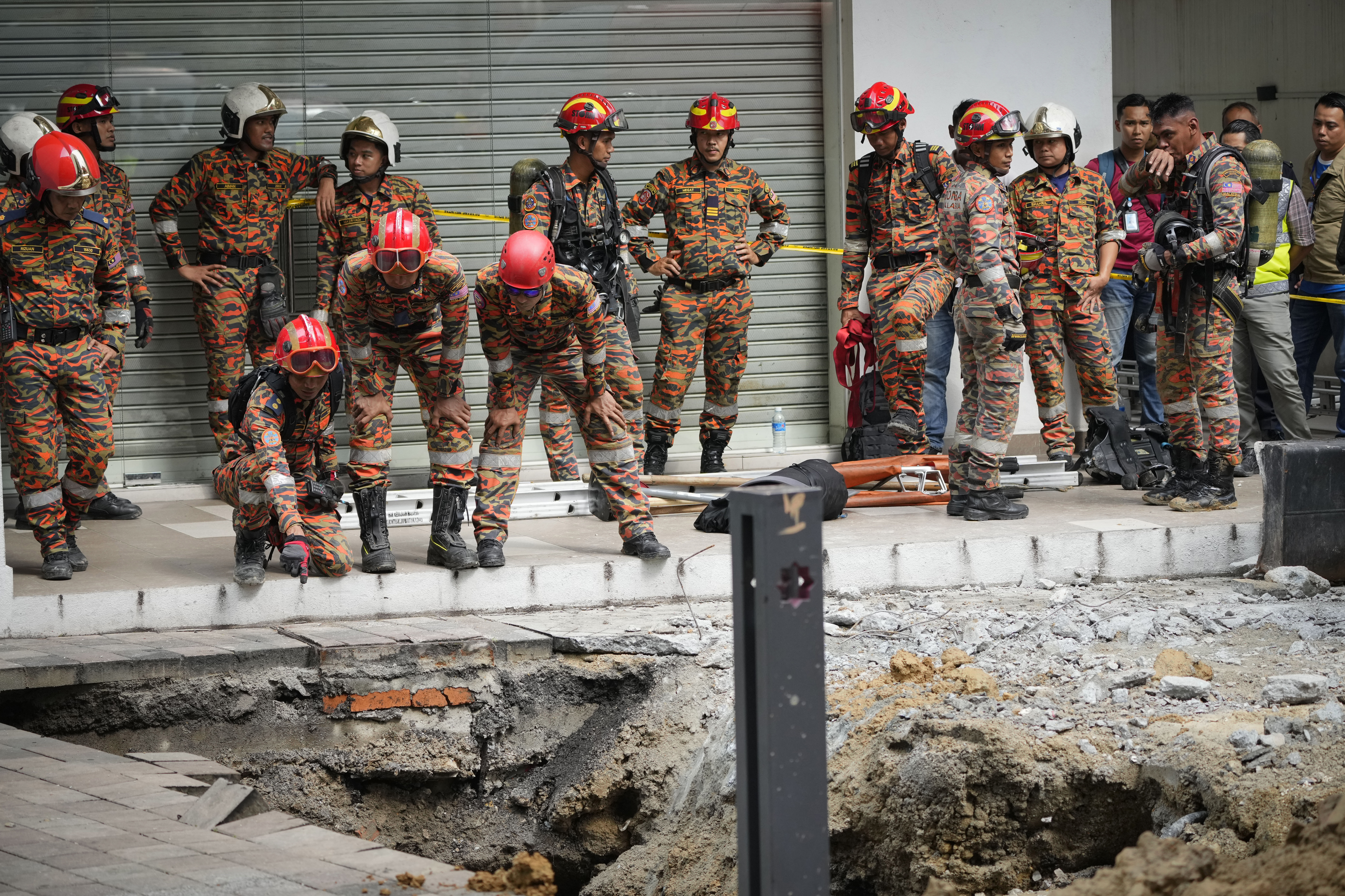 Fire and Rescue department checking on after receiving reports that a woman has fallen into the sinkhole after a section of the sidewalk caved in Kuala Lumpur, Friday, Aug. 23, 2024. 