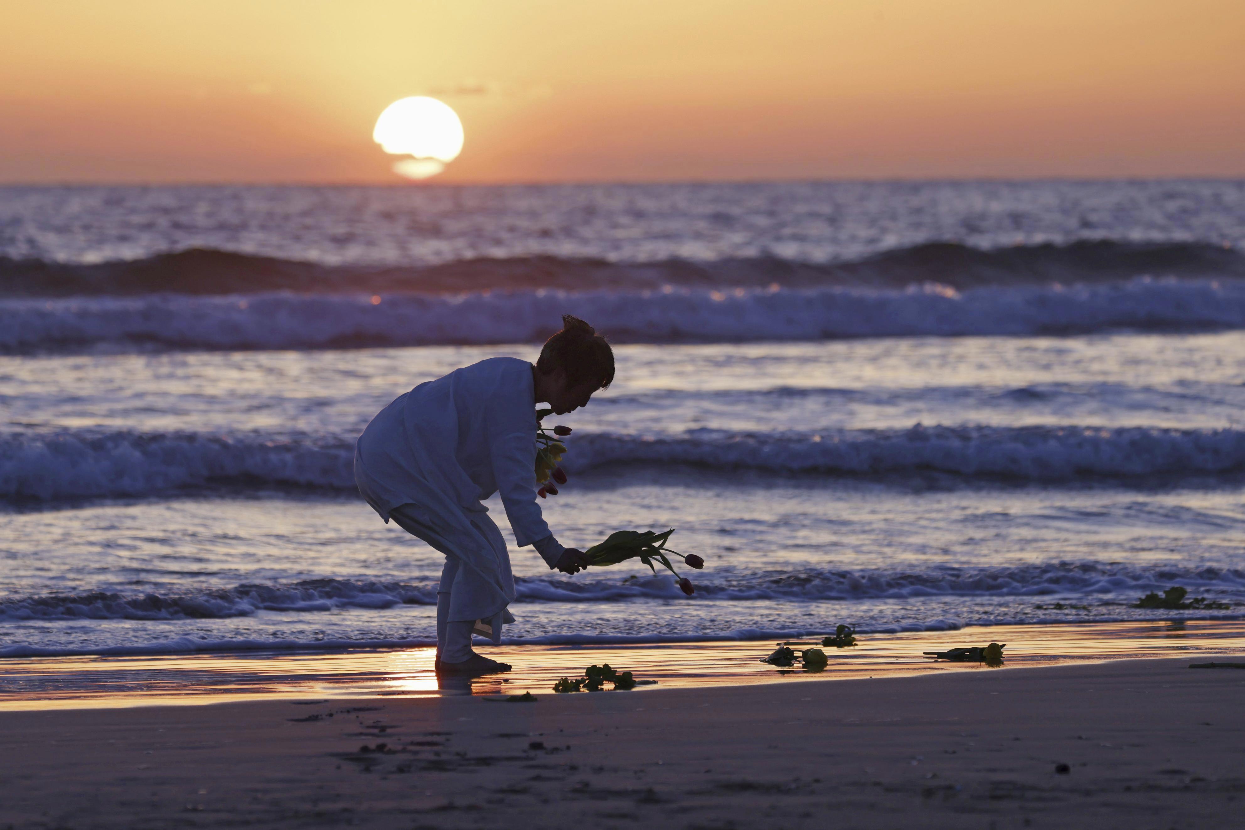 A woman places flowers on beach in Iwaki city, Fukushima prefecture on Saturday, March 11, 2023.