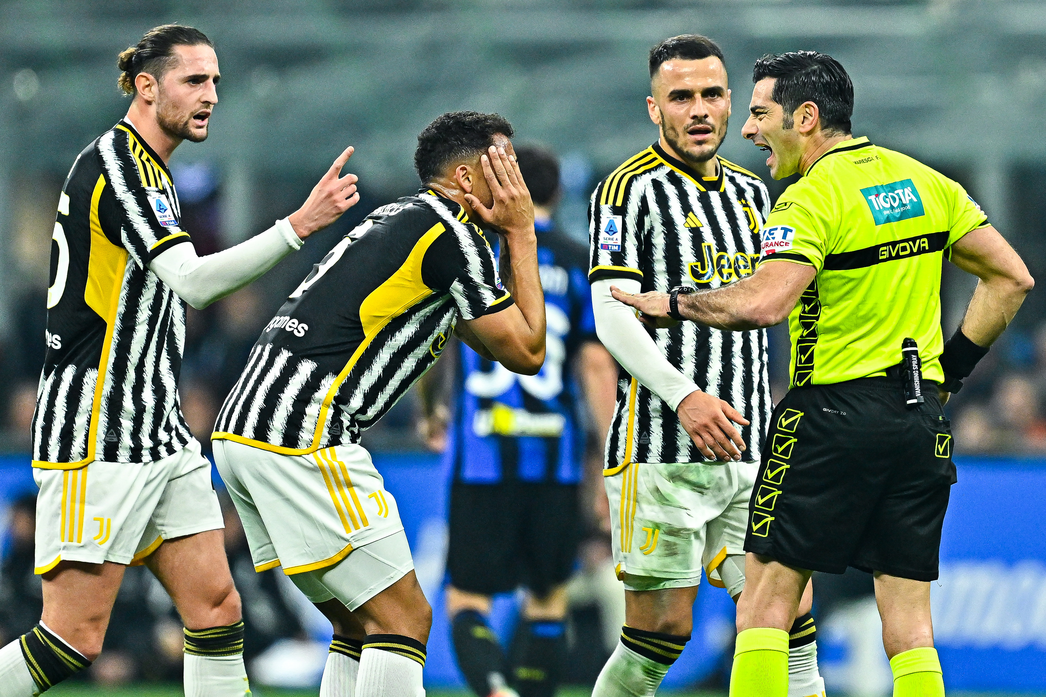Luiz Danilo of Juventus (second from left) complains with referee Fabio Maresca after being shown a yellow card during the Serie A match between FC Internazionale and Juventus.