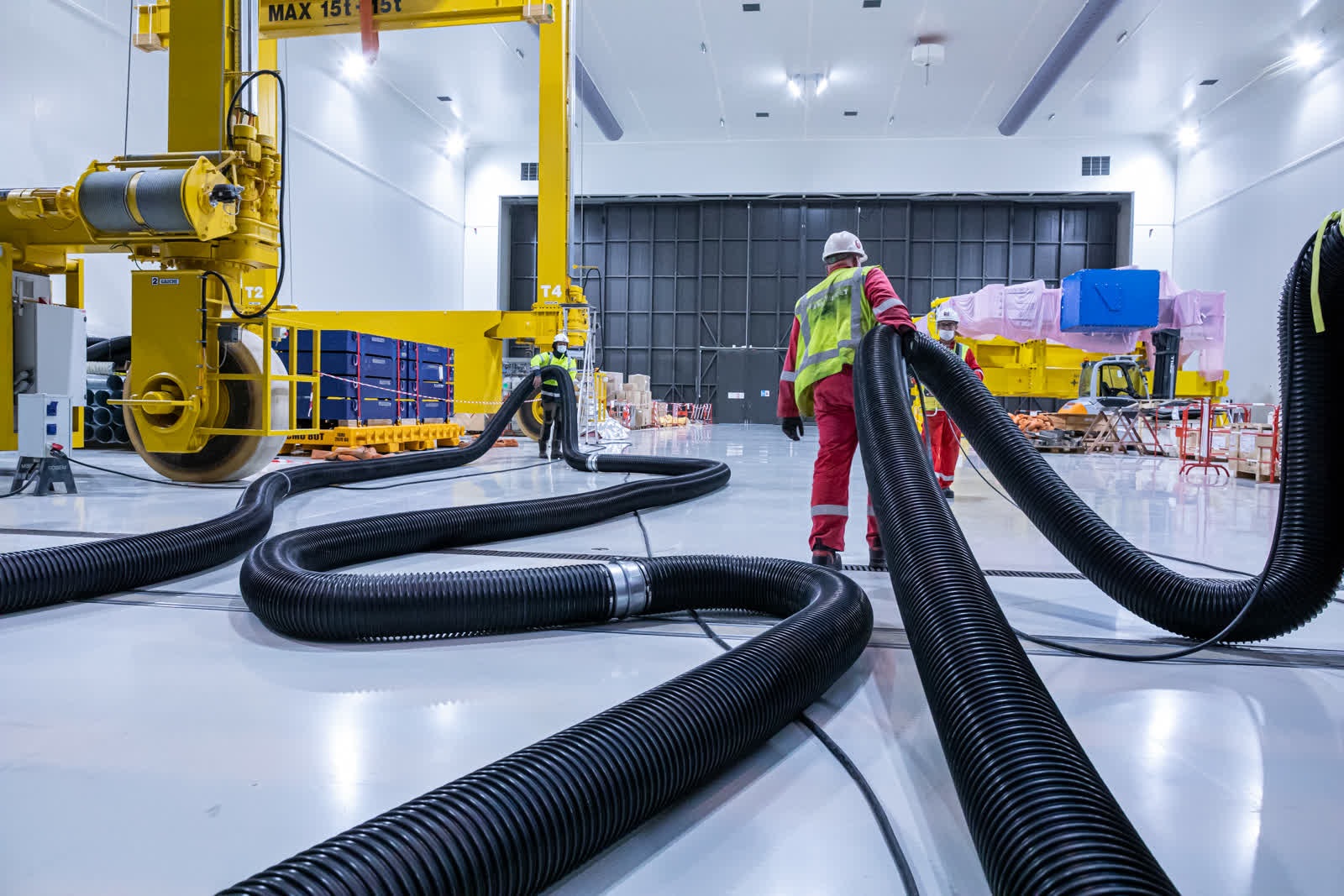 Workers carry exhaust pipes away from the assembly hall. These pipes are used to expel exhaust from trucks that deliver the large components to the clean facility.