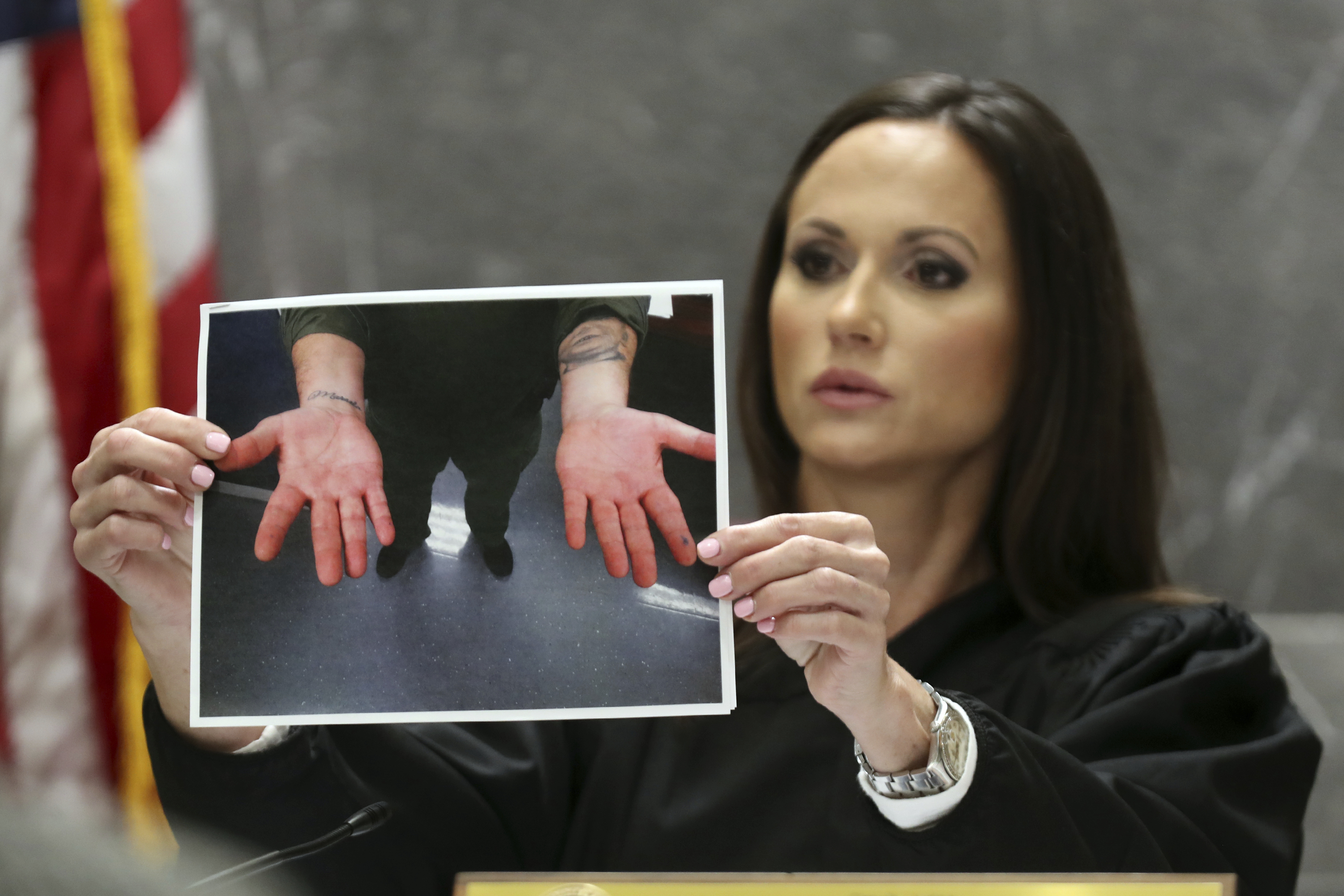 Judge Elizabeth Scherer holds a photograph of the hands of Broward jail guard Sgt. Ray Beltran after a November 2018 altercation between Beltran and Parkland school shooter Nikolas Cruz. 