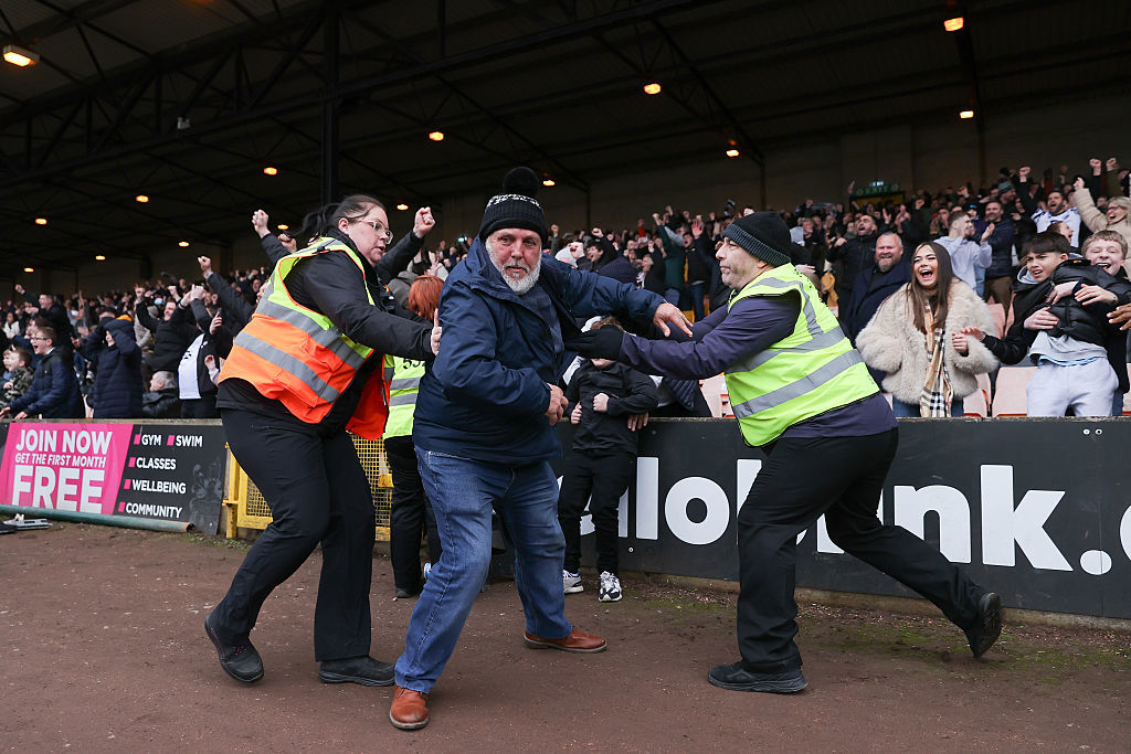 Stewards attempt to prevent a Port Vale fan from invading the pitch in the match against Sunderland.