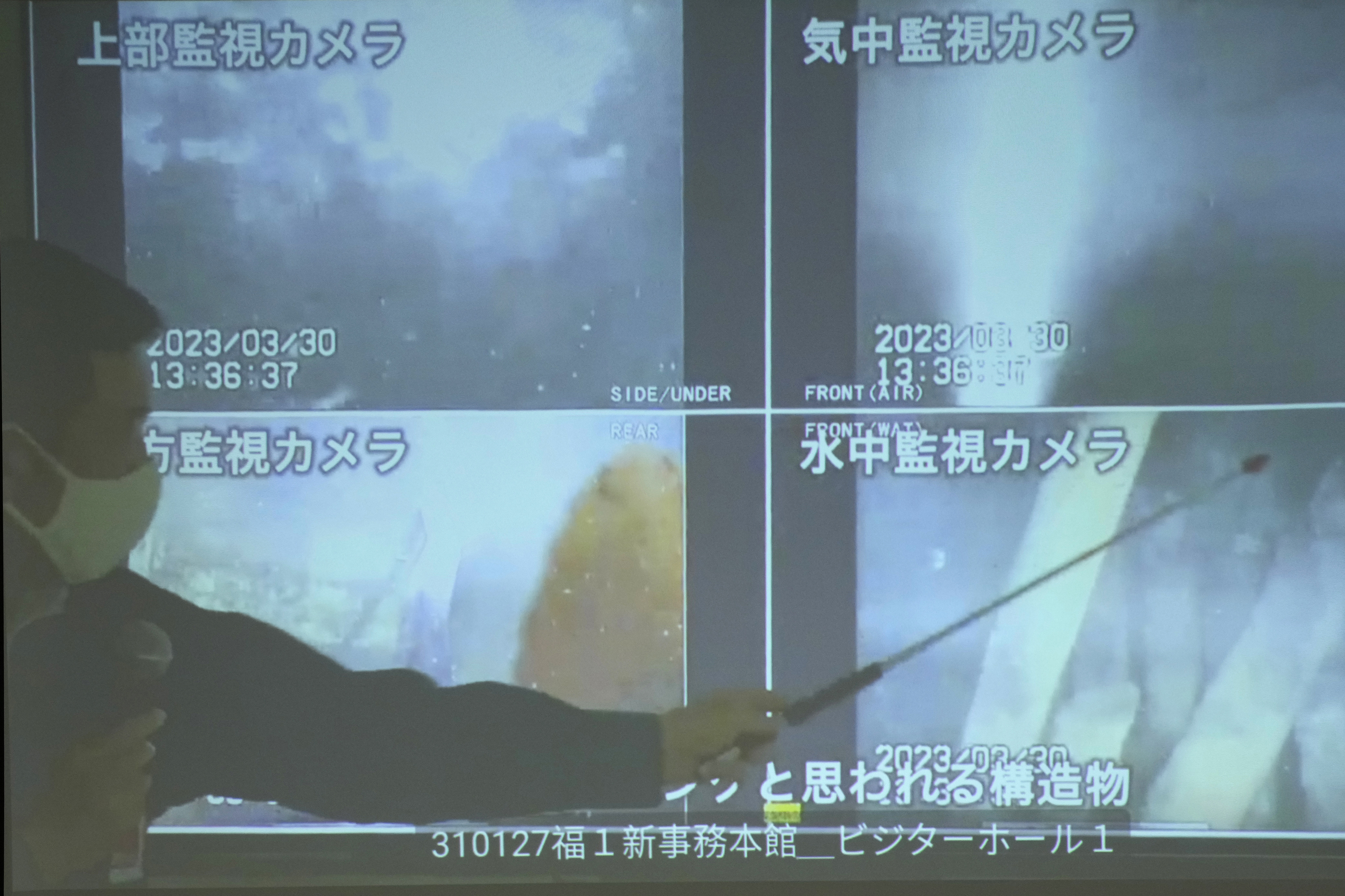 A spokesperson of the Tokyo Electric Power Company Holdings (TEPCO) shows photos captured by a robotic probe inside one of the three melted reactors at the tsunami-wrecked Fukushima nuclear power plant.