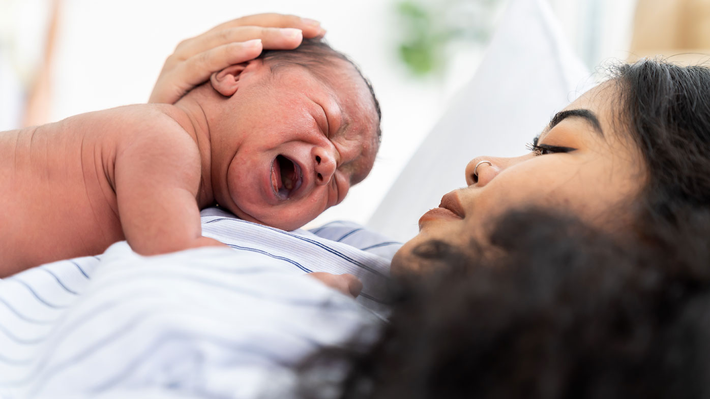 A new mother holds her crying baby.