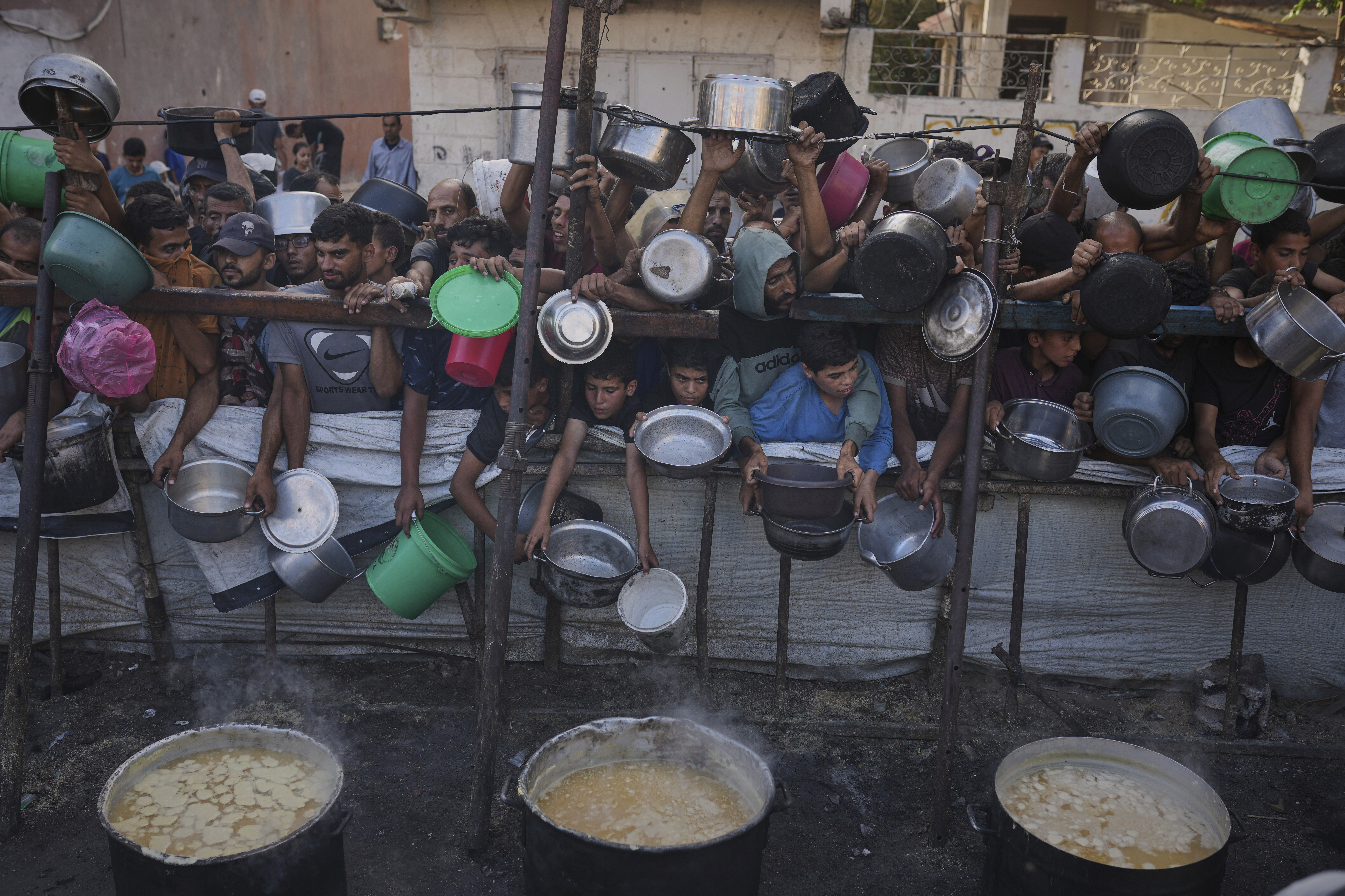 Palestinians struggle to get donated food at a community kitchen in Gaza City, northern Gaza Strip, Monday, July 14, 2025. (AP Photo/Jehad Alshrafi)