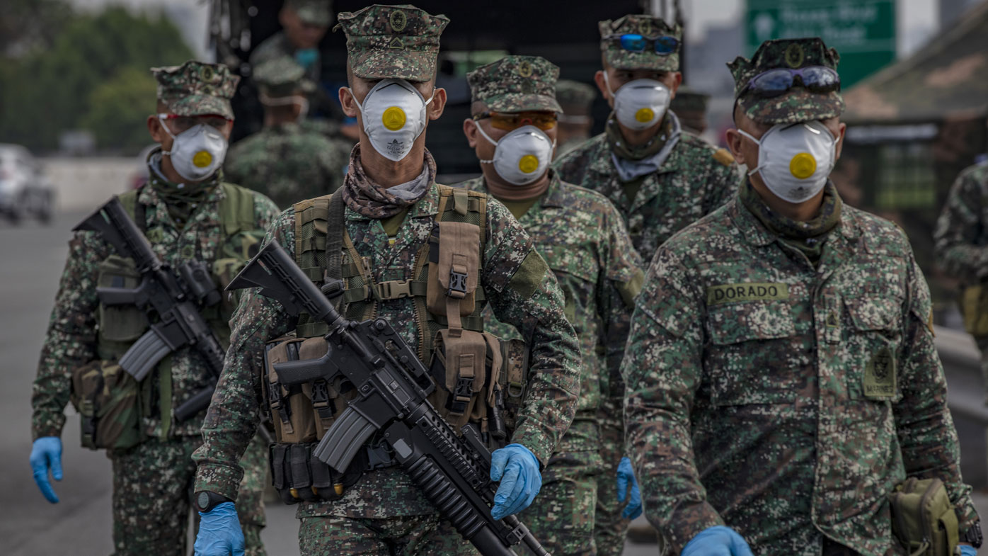 Filipino policemen wearing facemasks and gloves man a checkpoint as authorities begin implementing lockdown measures on March 16, 2020 in Las Pinas in Metro Manila.