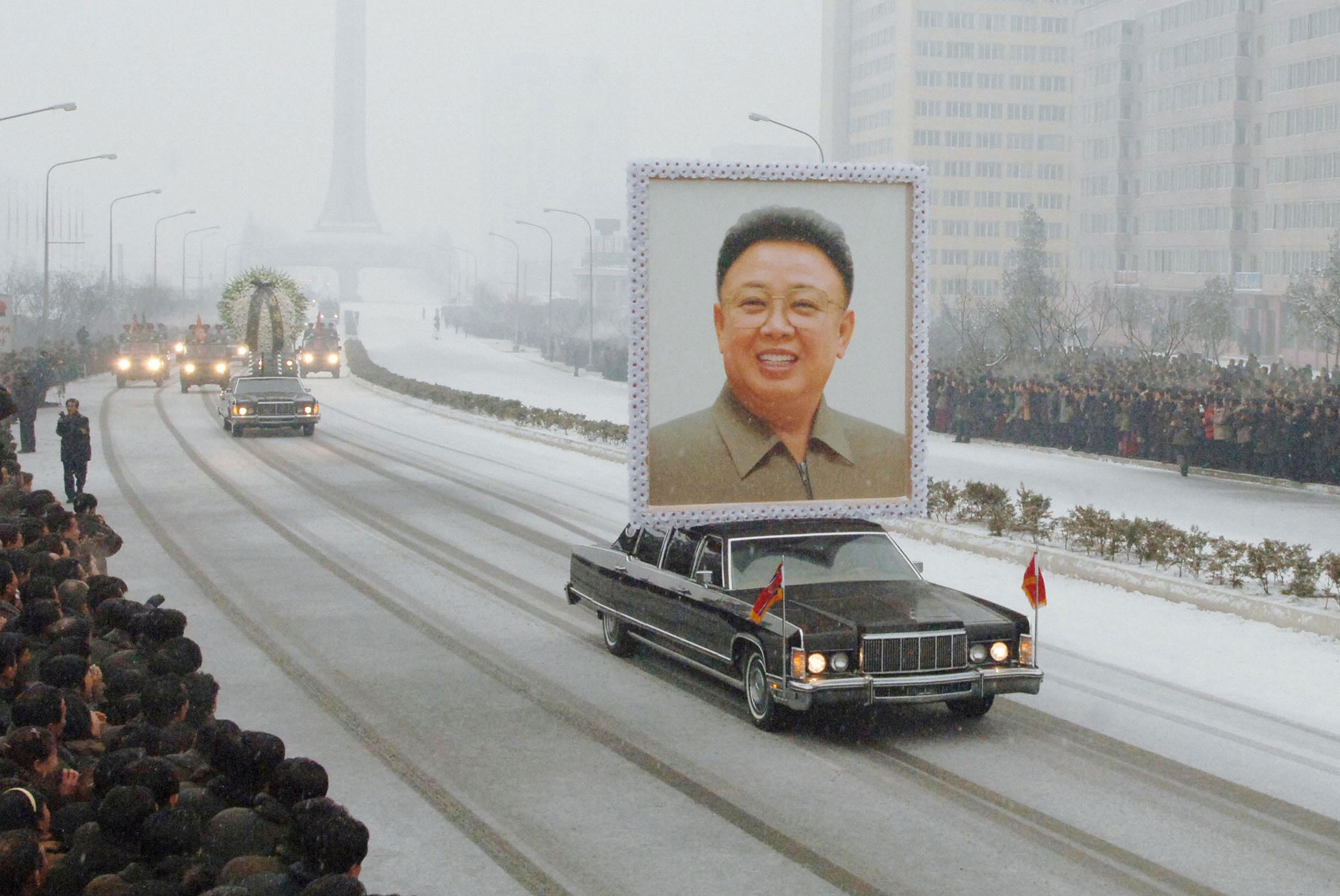 The funeral motorcade including a car exhibiting a large portrait of the late Kim Jong Il drives through Pyongyang on a snowy road on December 28, 2011.