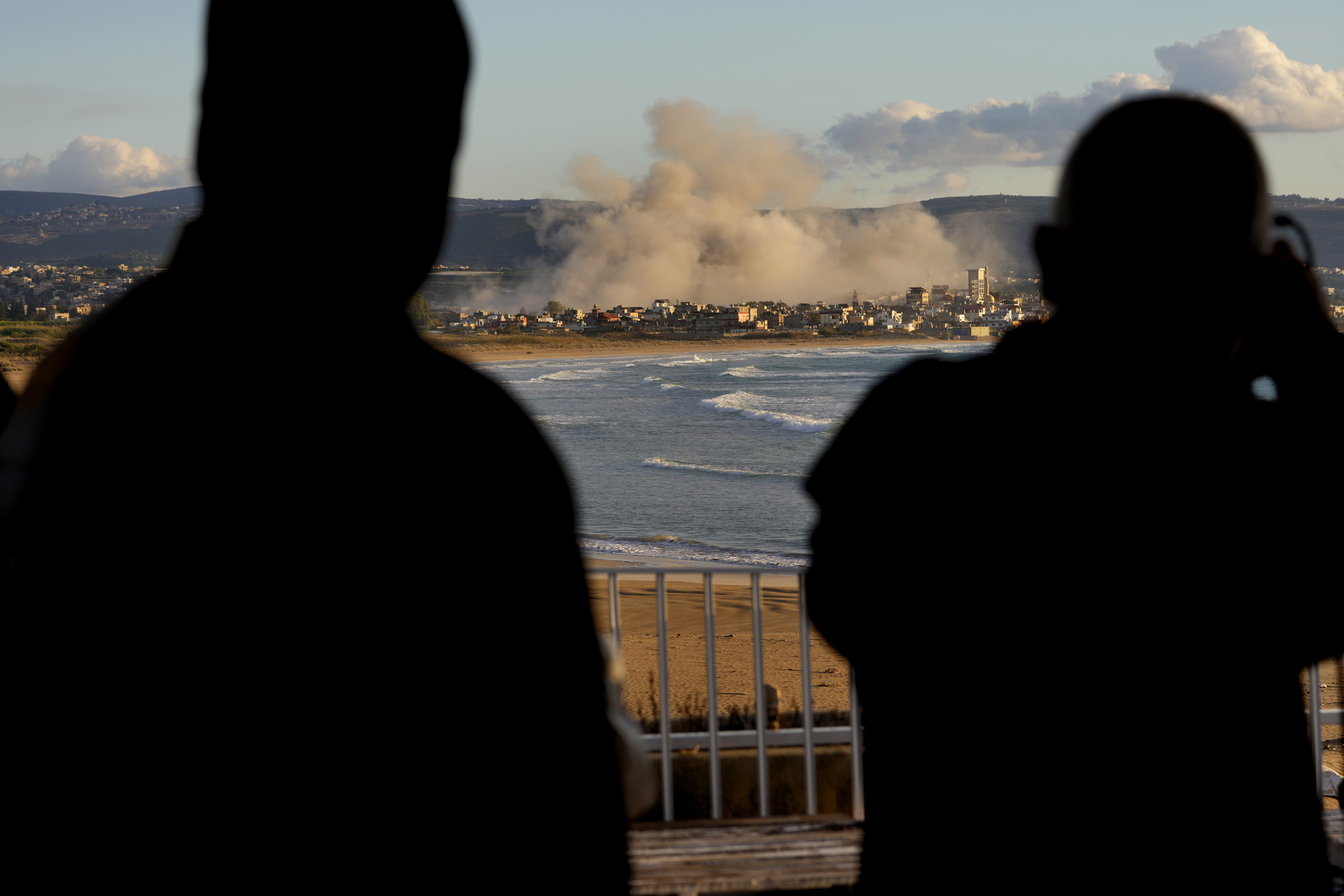 Los periodistas observan el humo que se eleva entre los edificios afectados por los ataques aéreos israelíes cerca del campo de refugiados palestinos de Rashidiyeh, visto desde la ciudad de Tiro, en el sur del Líbano, el martes 26 de noviembre de 2024.