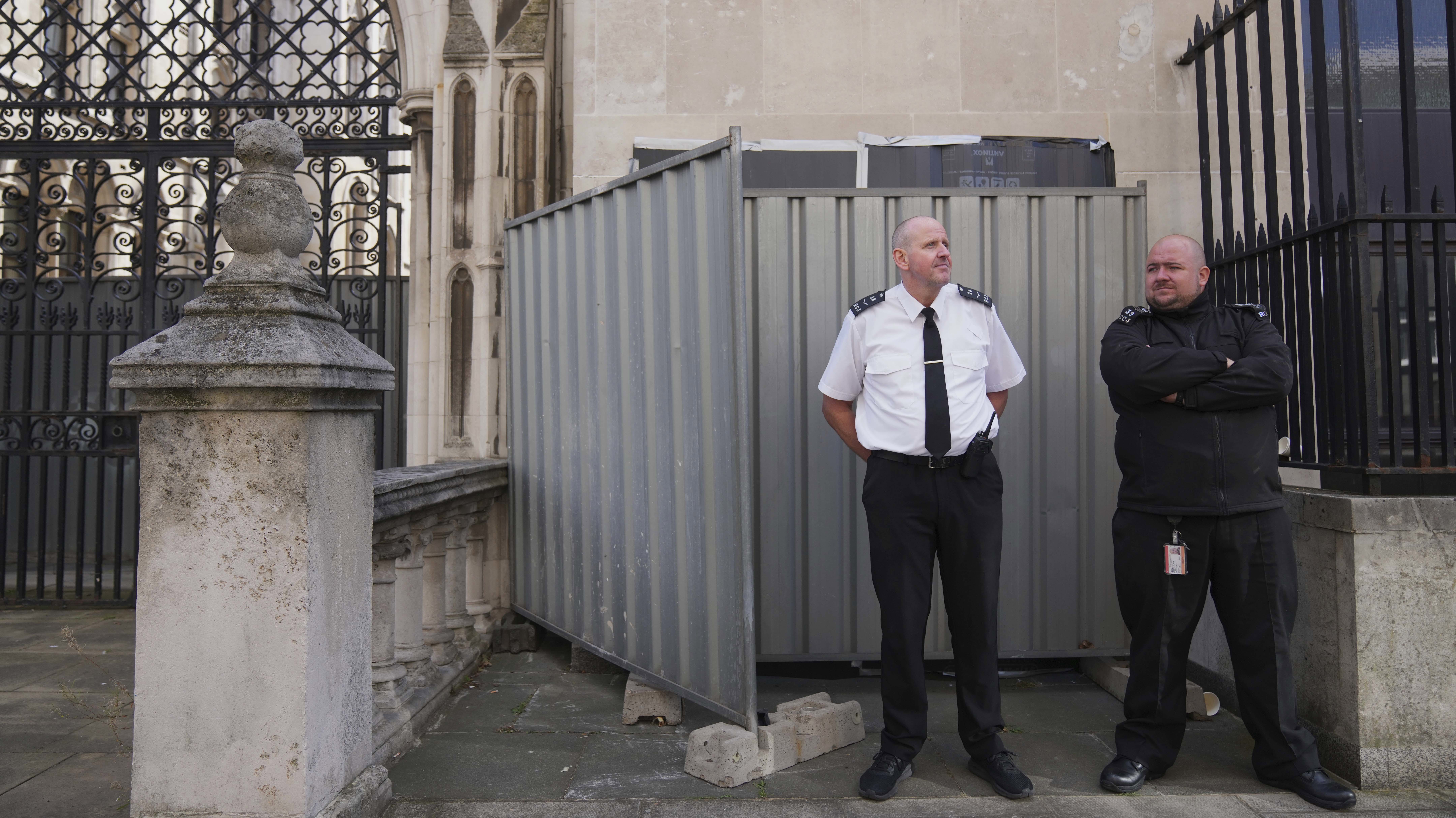 Security officials stand in front of large sheets of black plastic and two metal barriers which conceal street artist Banksy's latest artwork.