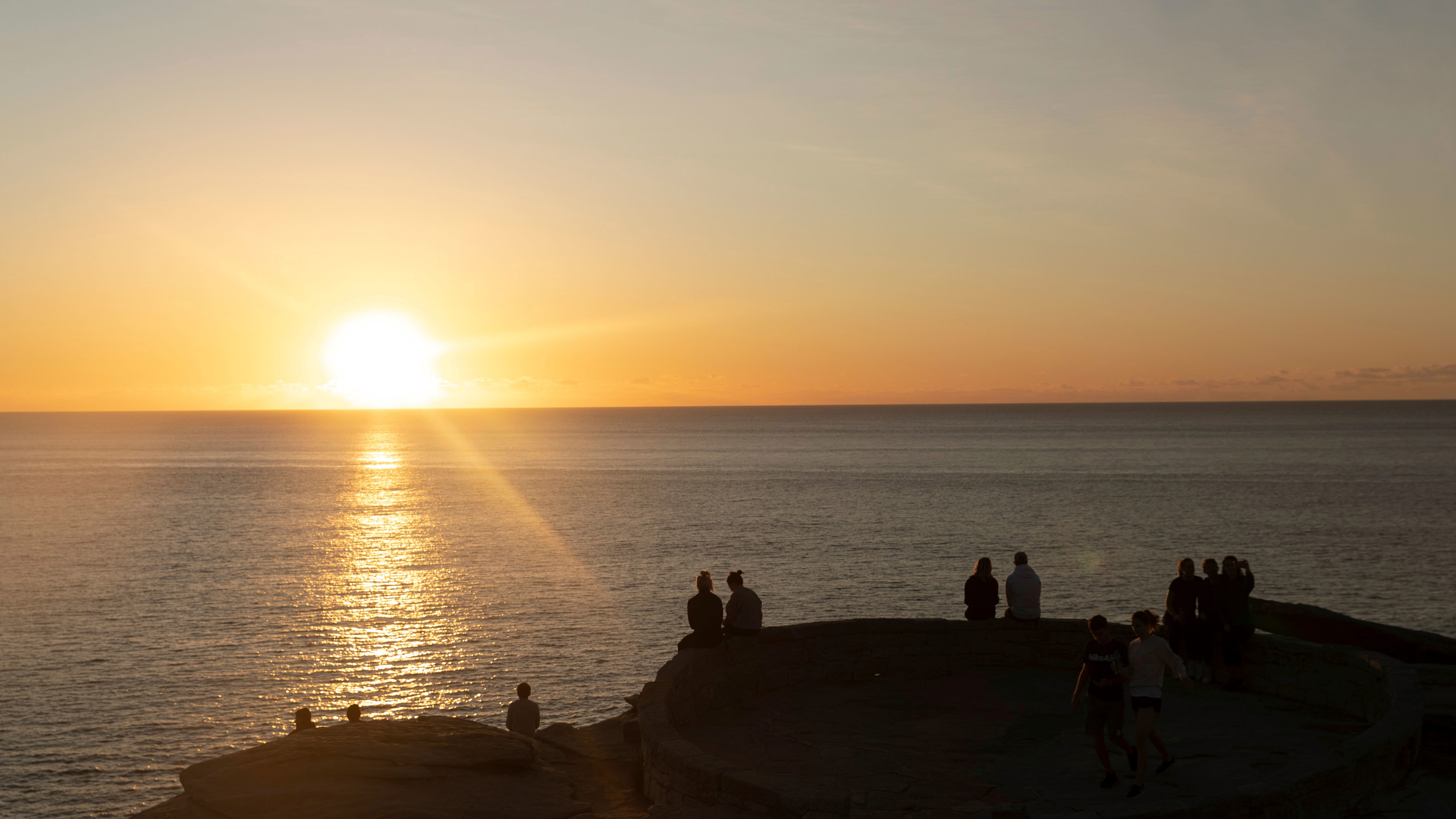 People watch the sunrise at Mackenzie's Point, Bondi.