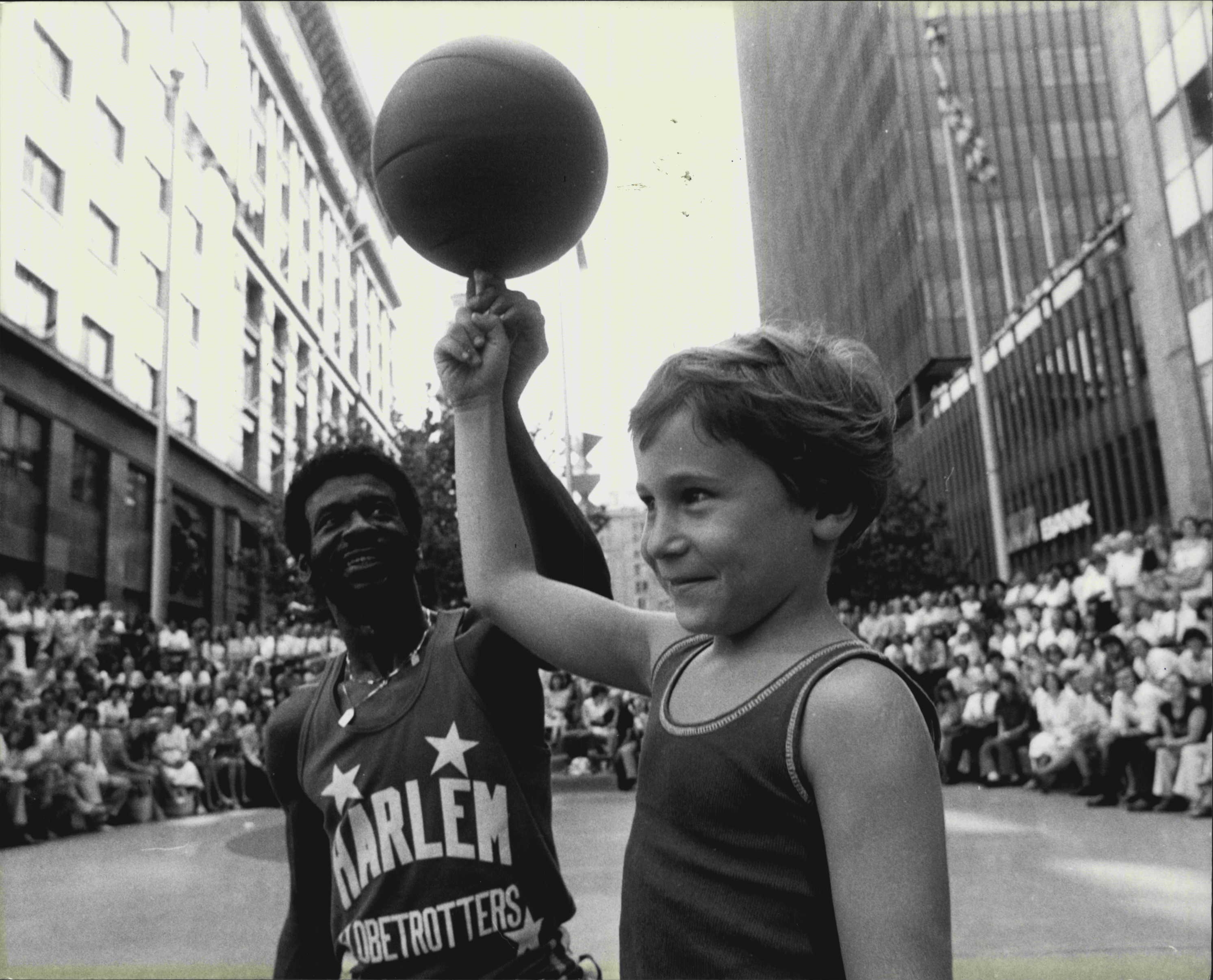 The Harlem Globetrotters at Martin Place Amphitheatre giving a lunch hour display of theur talents. Julian Cappe, 7, of Bellevue Hill, practices with Larry Rivers one of the Globetrotters. March 3, 1980. (Photo by John Nobley/Fairfax Media).