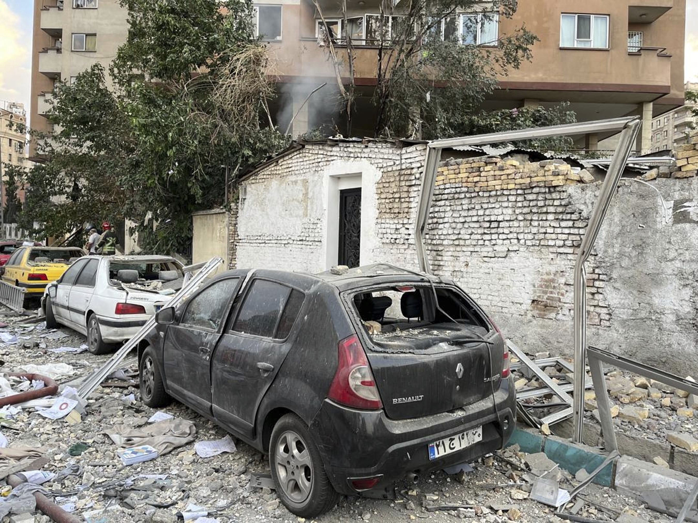 Debris from an apartment building is seen on top of parked cars after a strike in Tehran.