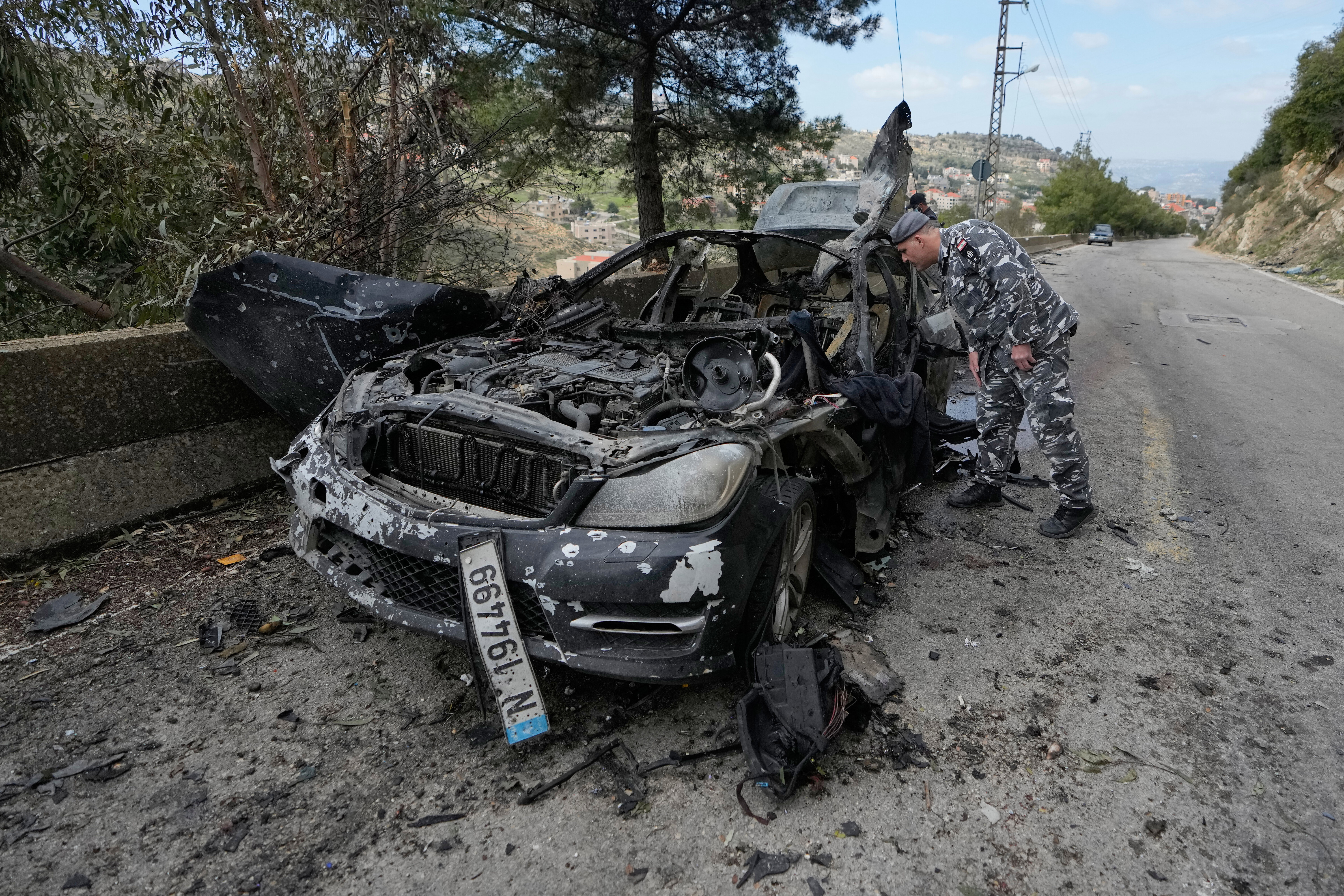 A policeman checks the charred car that was carrying Hezbollah's al-Manar TV correspondent Ali Shoeib, Beirut's based Al-Mayadeen TV reporter Fatima Ftouni and her brother, video journalist Mohammed Ftouni, before they were killed in an Israeli airstrike, in the town of Jezzine, south Lebanon, Saturday, March 28, 2026. (AP Photo/Mohammed Zaatari)