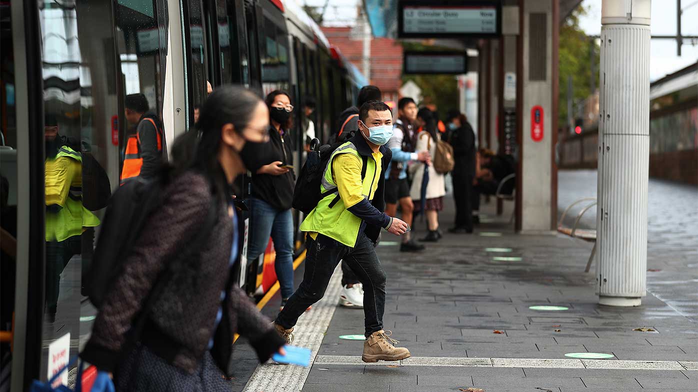 Commuters wearing masks disembark from the light rail at Central Station.