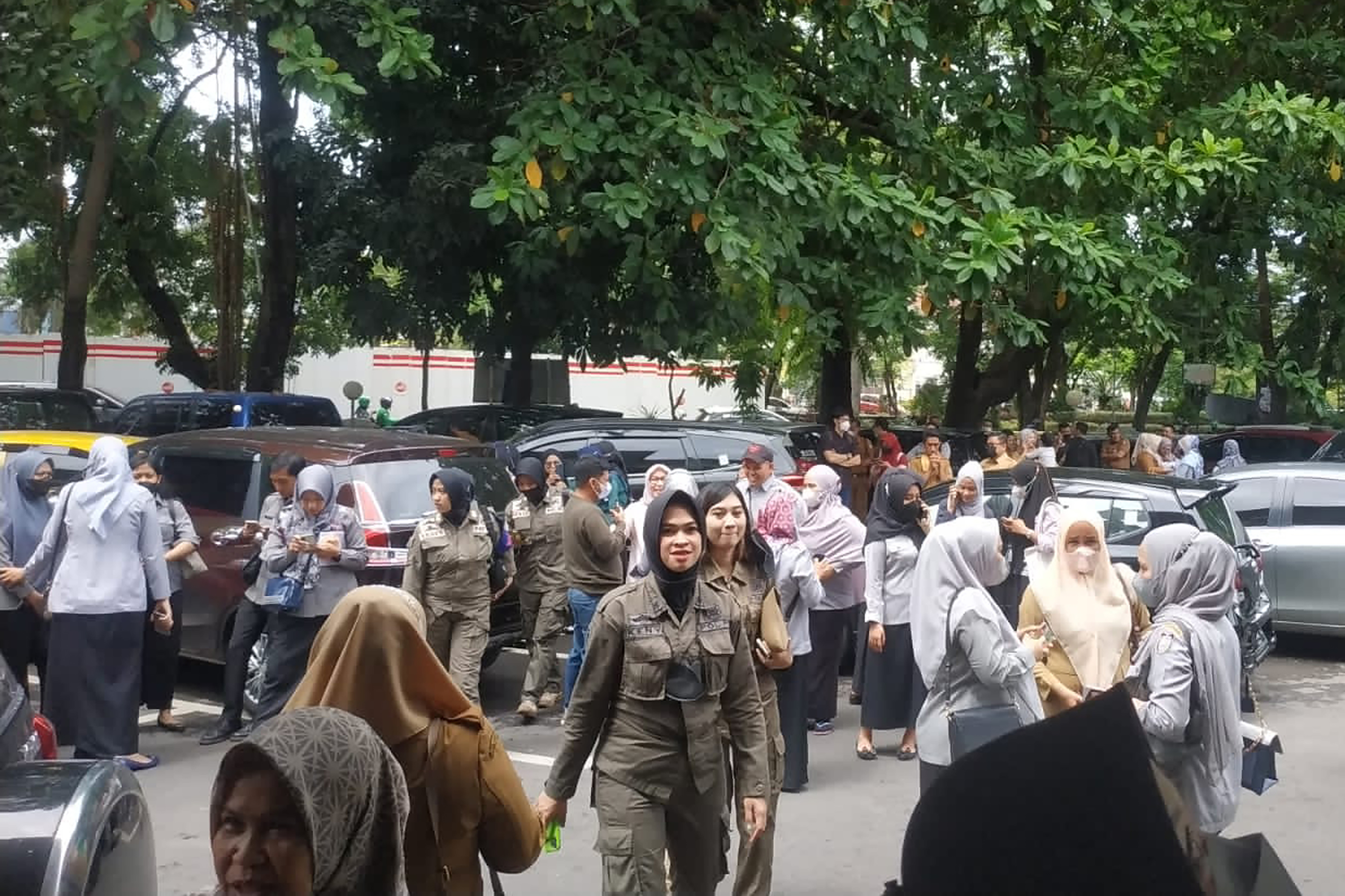 People wait outside after they evacuate a government building following an earthquake, in Makassar, South Sulawesi, Indonesia. 