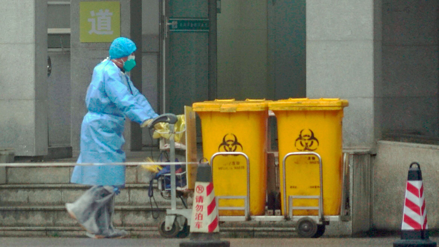 Staff move bio-waste containers past the entrance of the Wuhan Medical Treatment Center, where some infected with a new virus are being treated.
