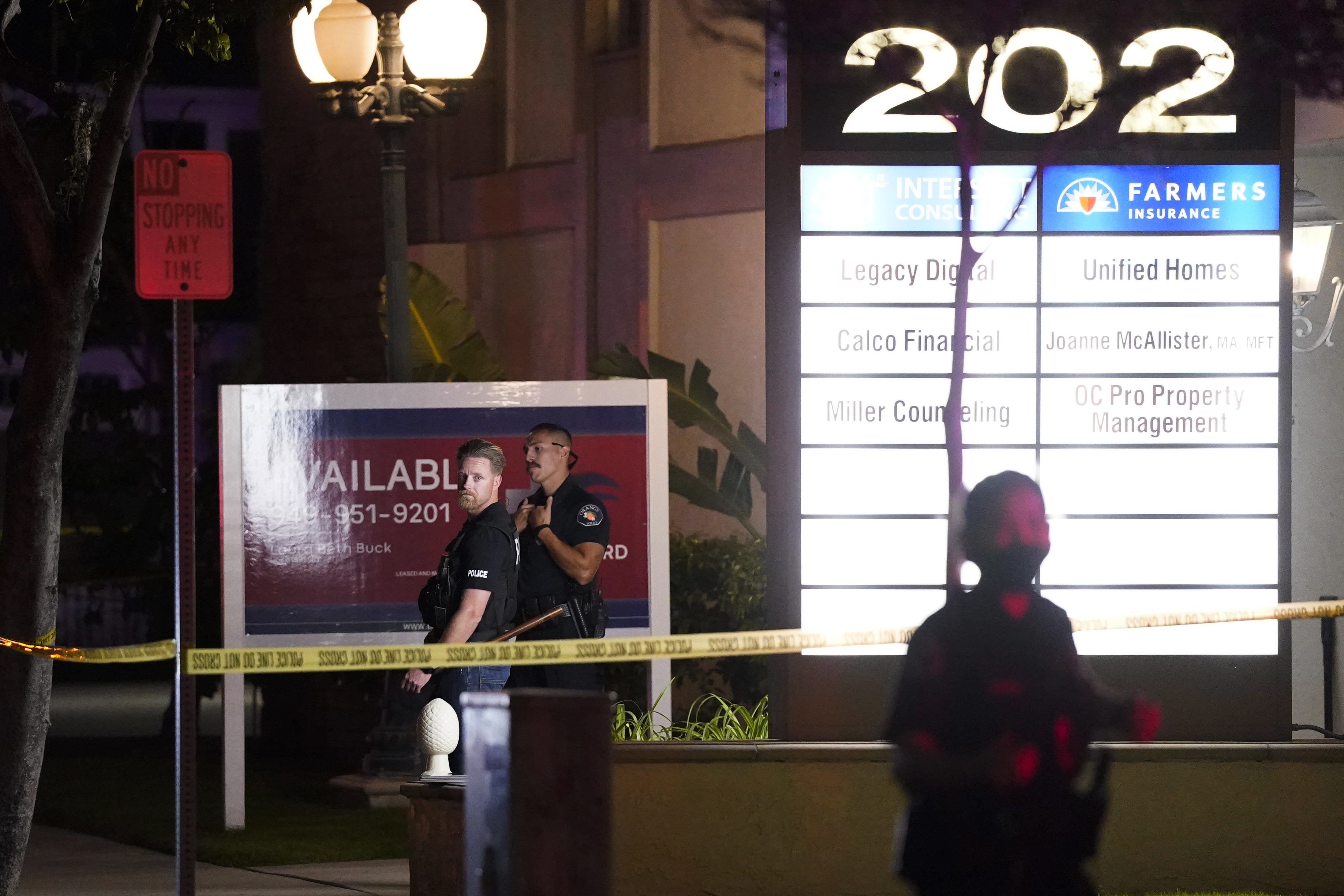 Police officers stand outside a business building where a shooting occurred in Orange. Four people are dead, including a child.