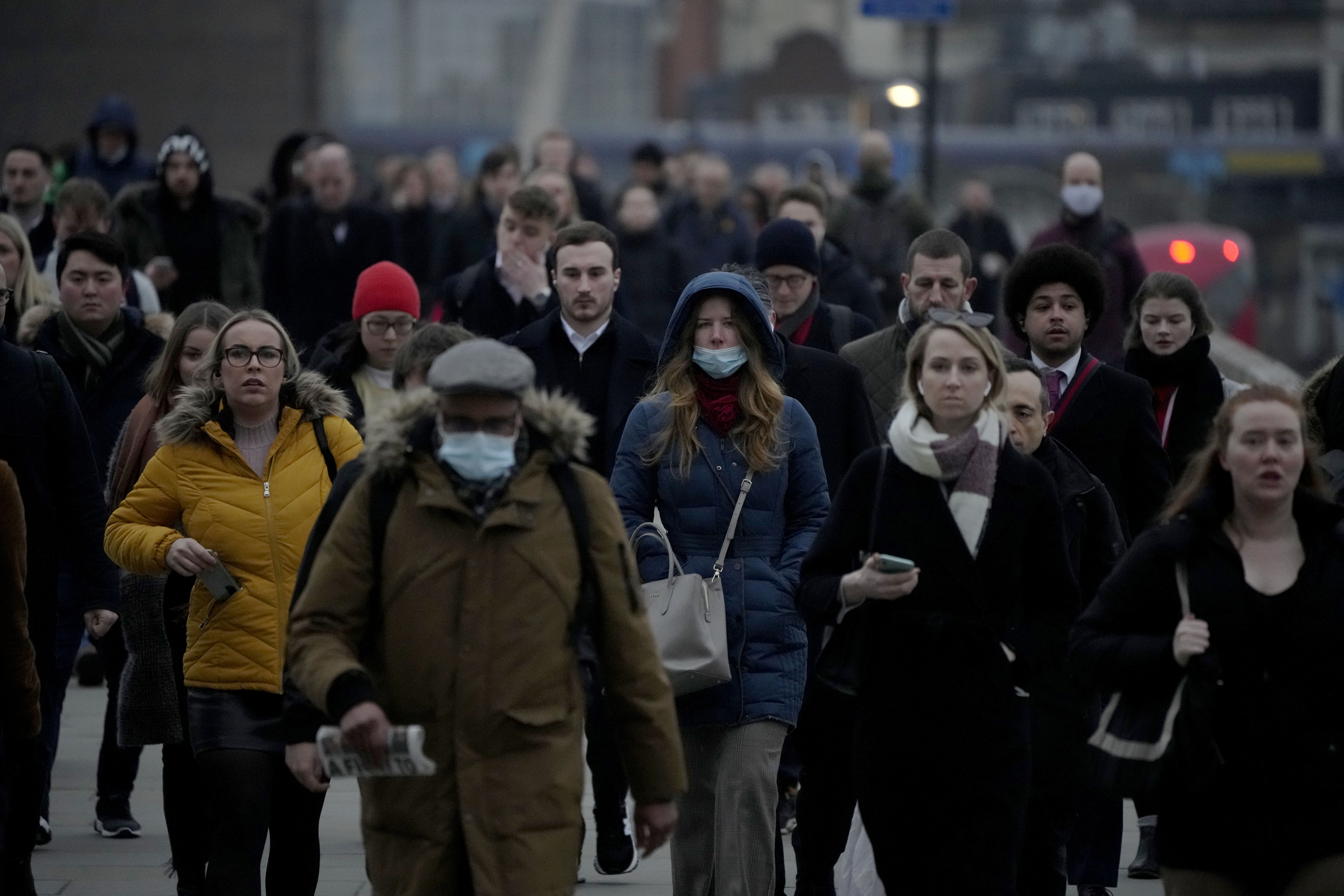 Workers walk over London Bridge towards the City of London financial district during the morning rush hour, in London, Monday, January 24, 2022.