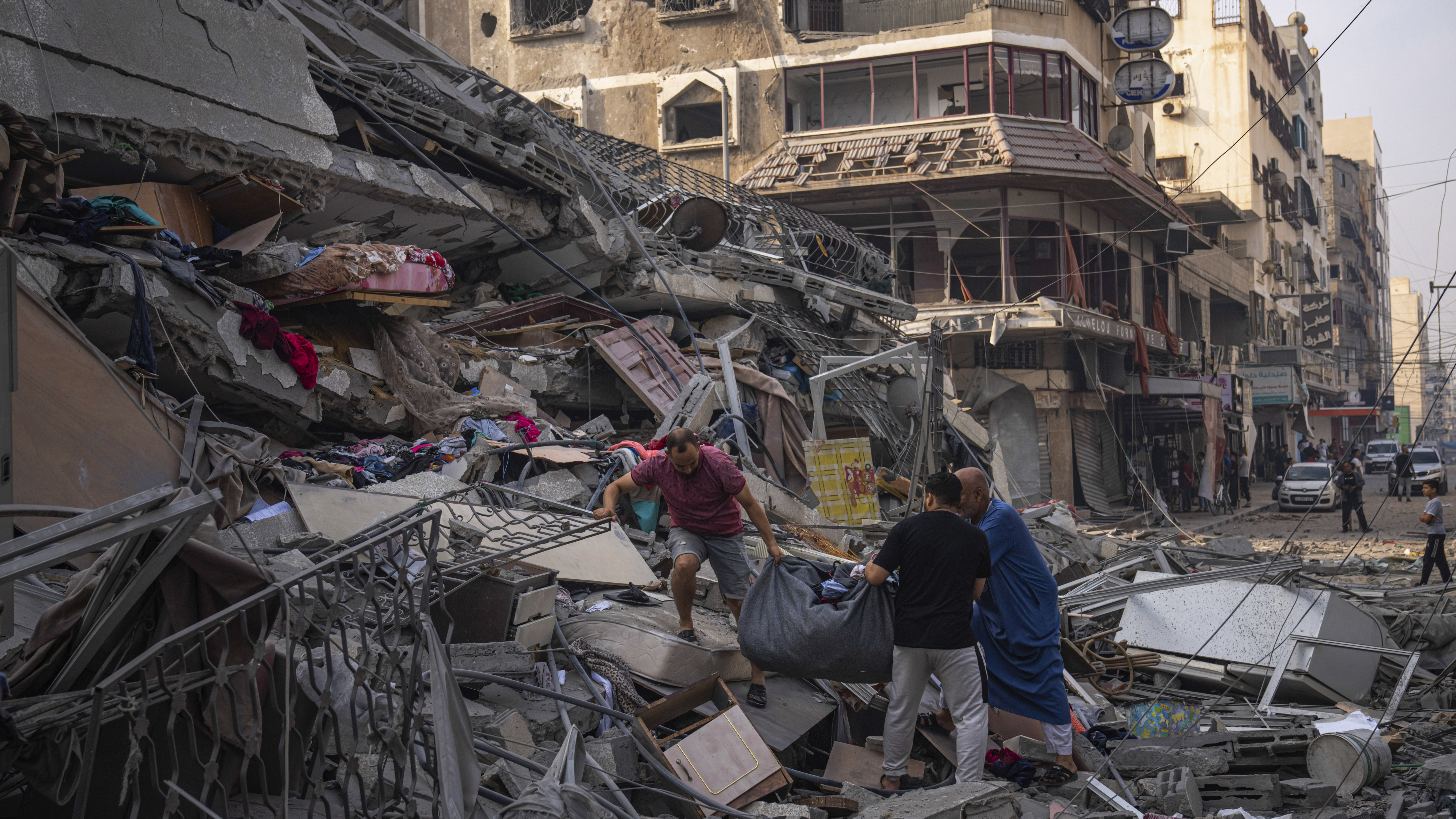 Palestinians scour the debris from the rubble of a building after it was struck by an Israeli airstrike, in Gaza City.