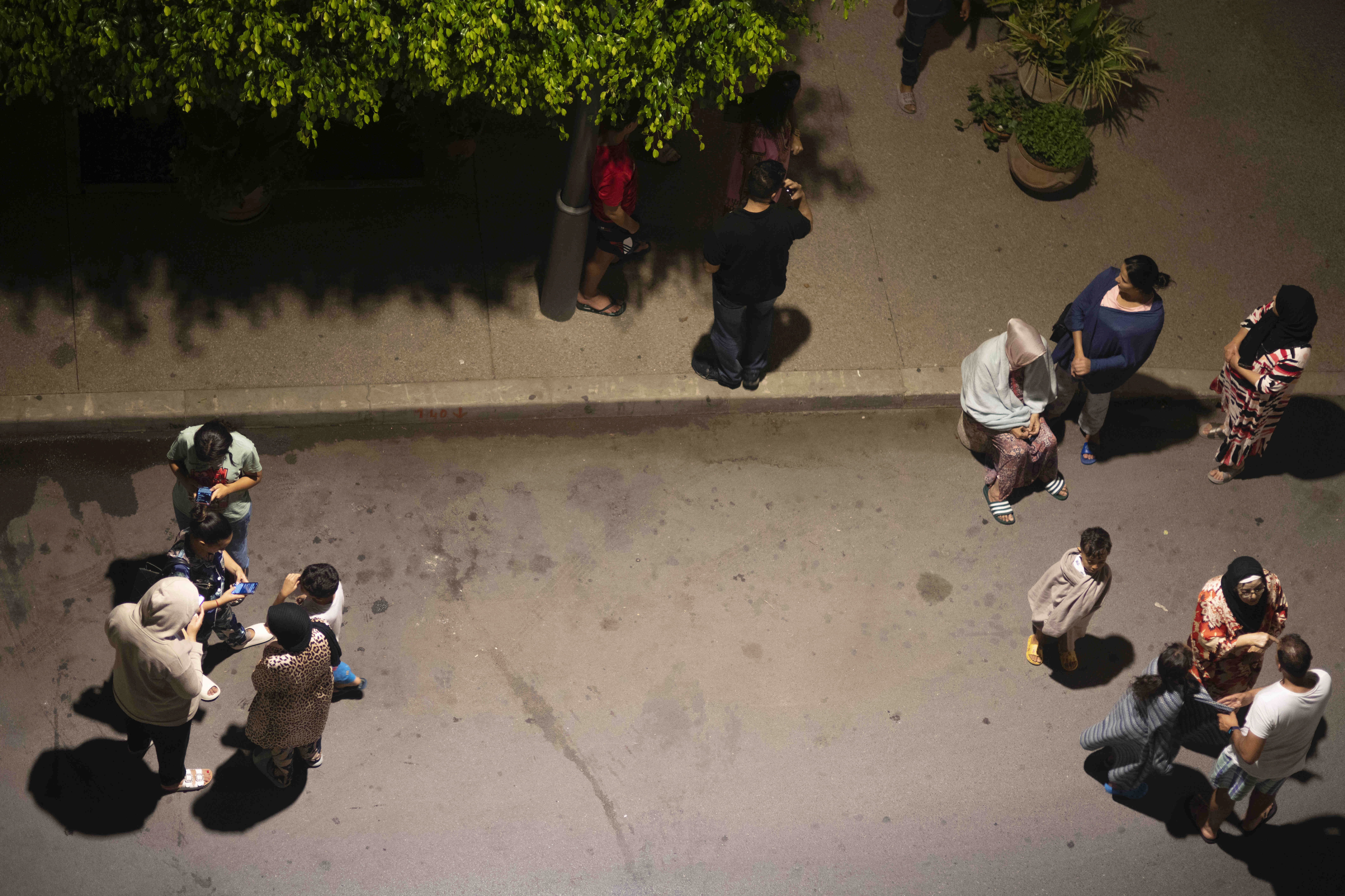 People take shelter and check for news on their mobile phones after an earthquake in Rabat, Morocco, Friday, Sept. 8, 2023. 