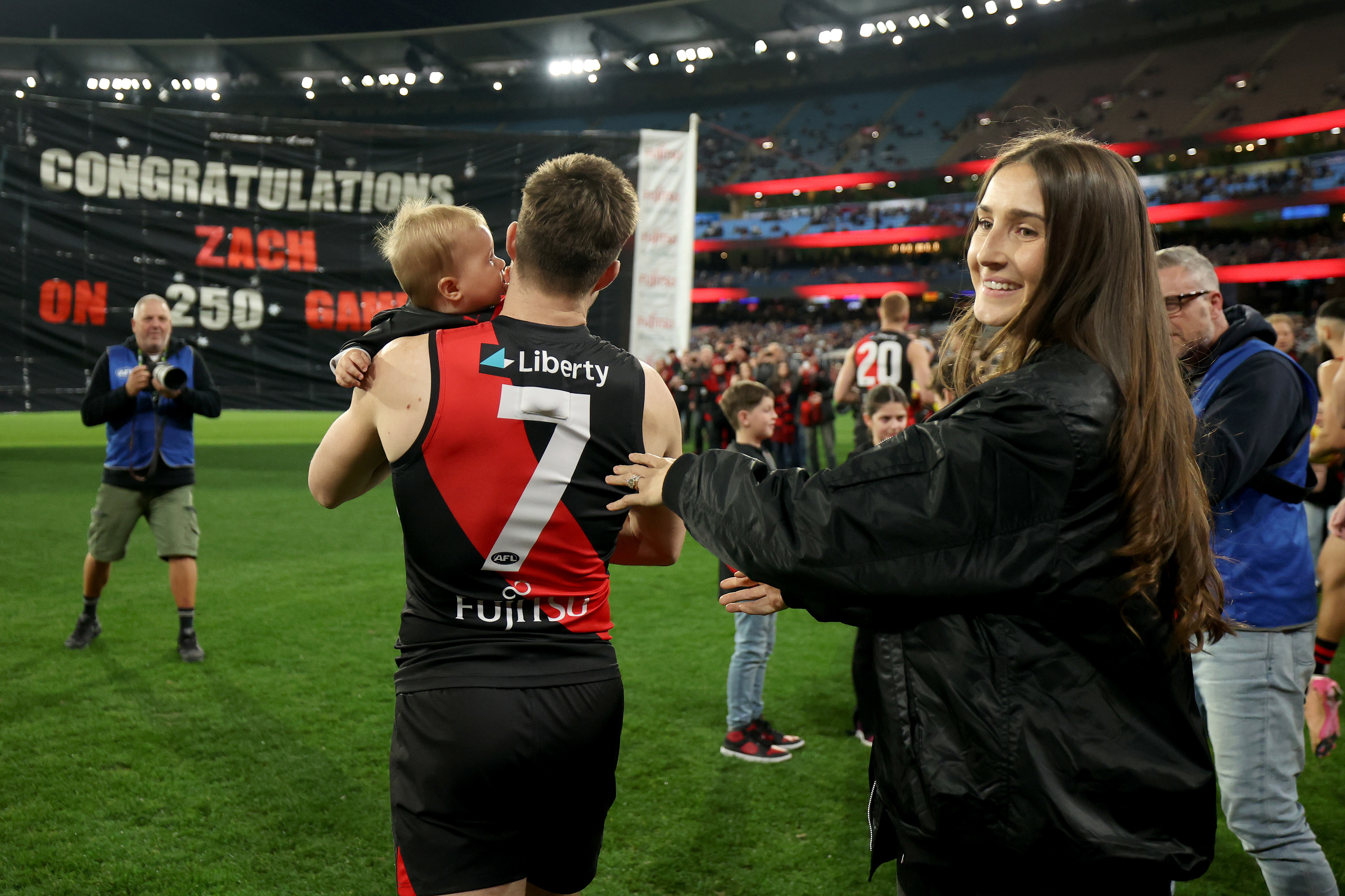 Zach Merrett of the Bombers is congratulated by his wife Alexandra and son Jude during his 250th game.