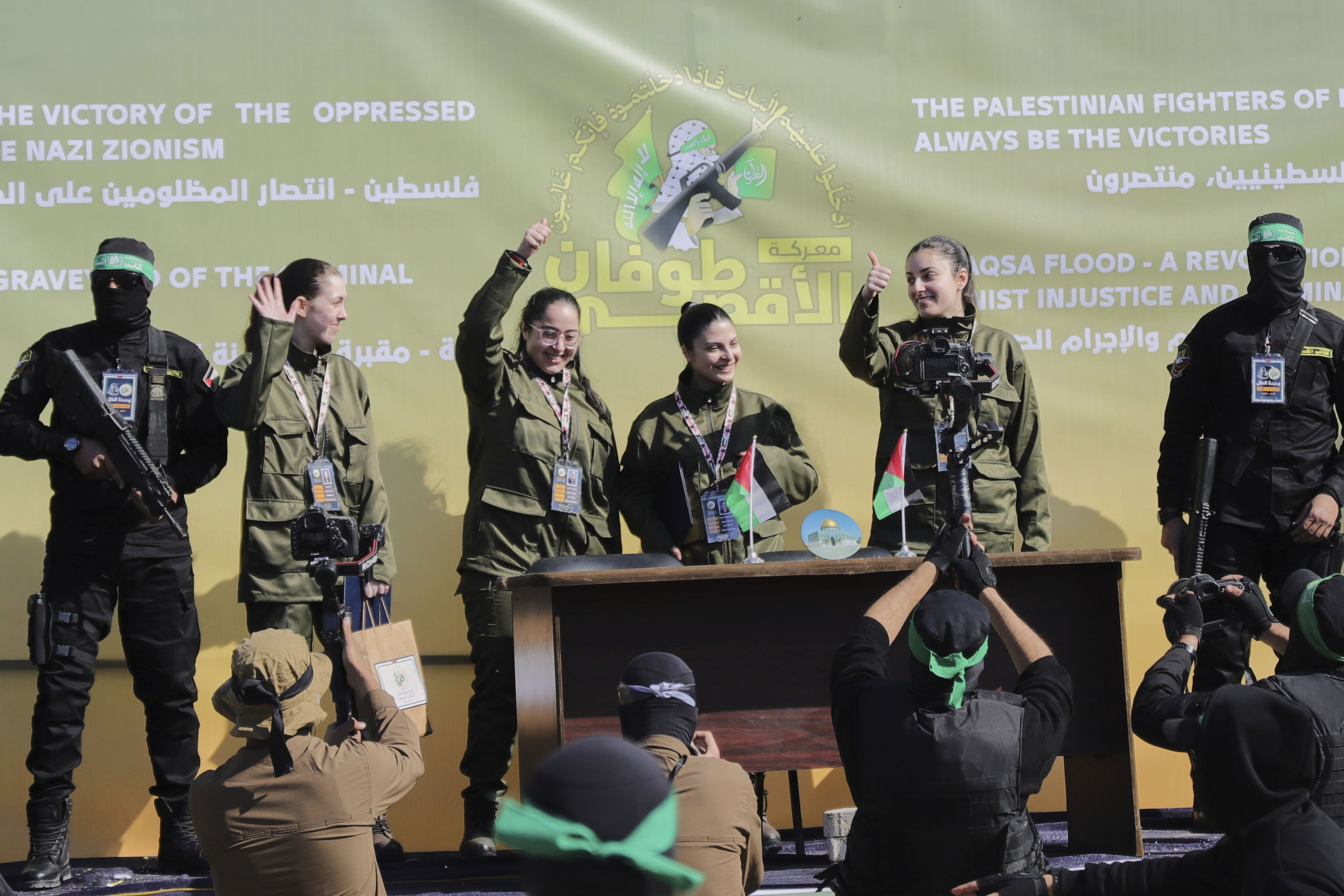 Israeli female soldier hostages wave at a Palestinian crowd 