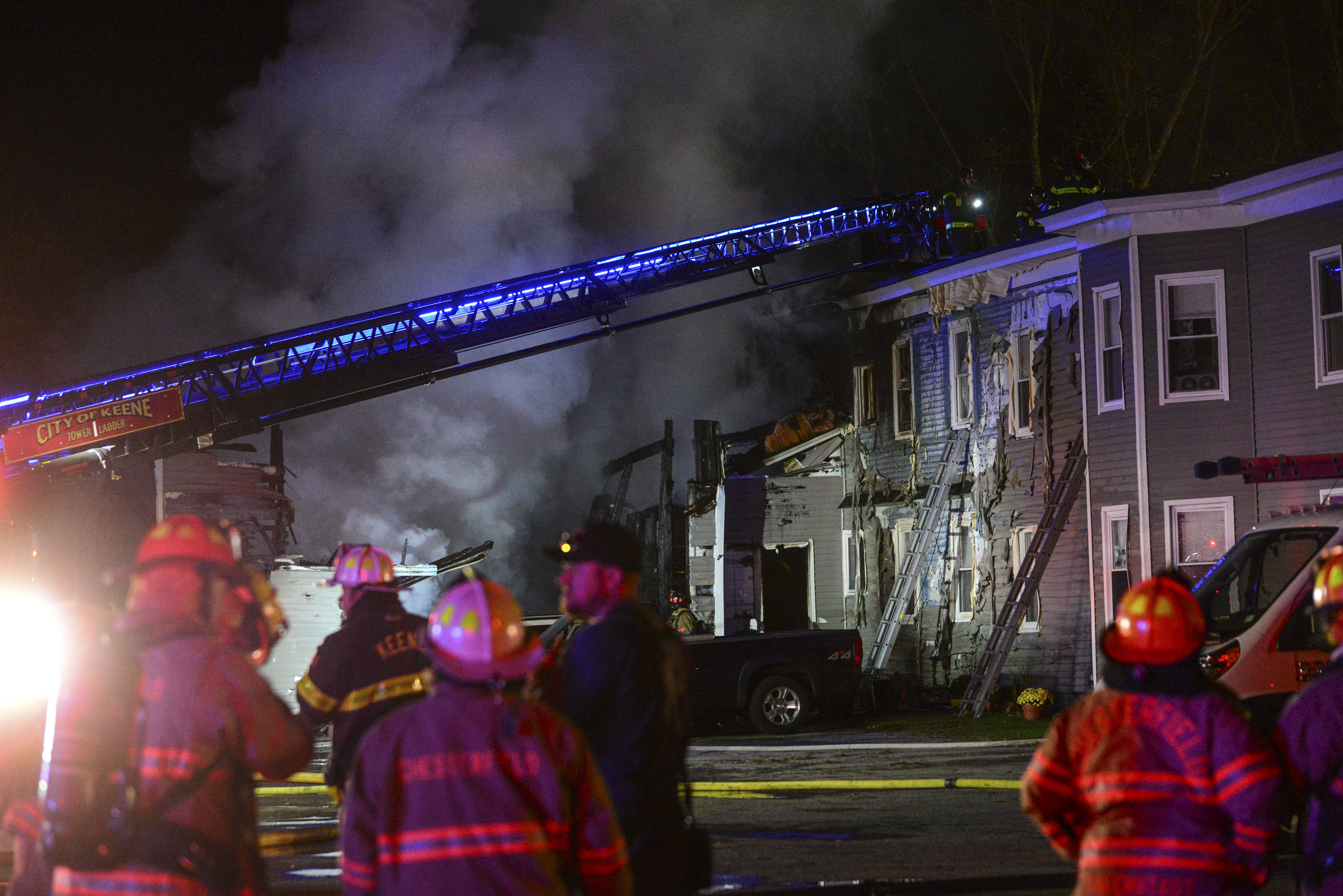 Fire departments work to extinguish a fire after a single-engine plane crashed near the building Friday, Oct. 21, 2022, in Keene, N.H.  