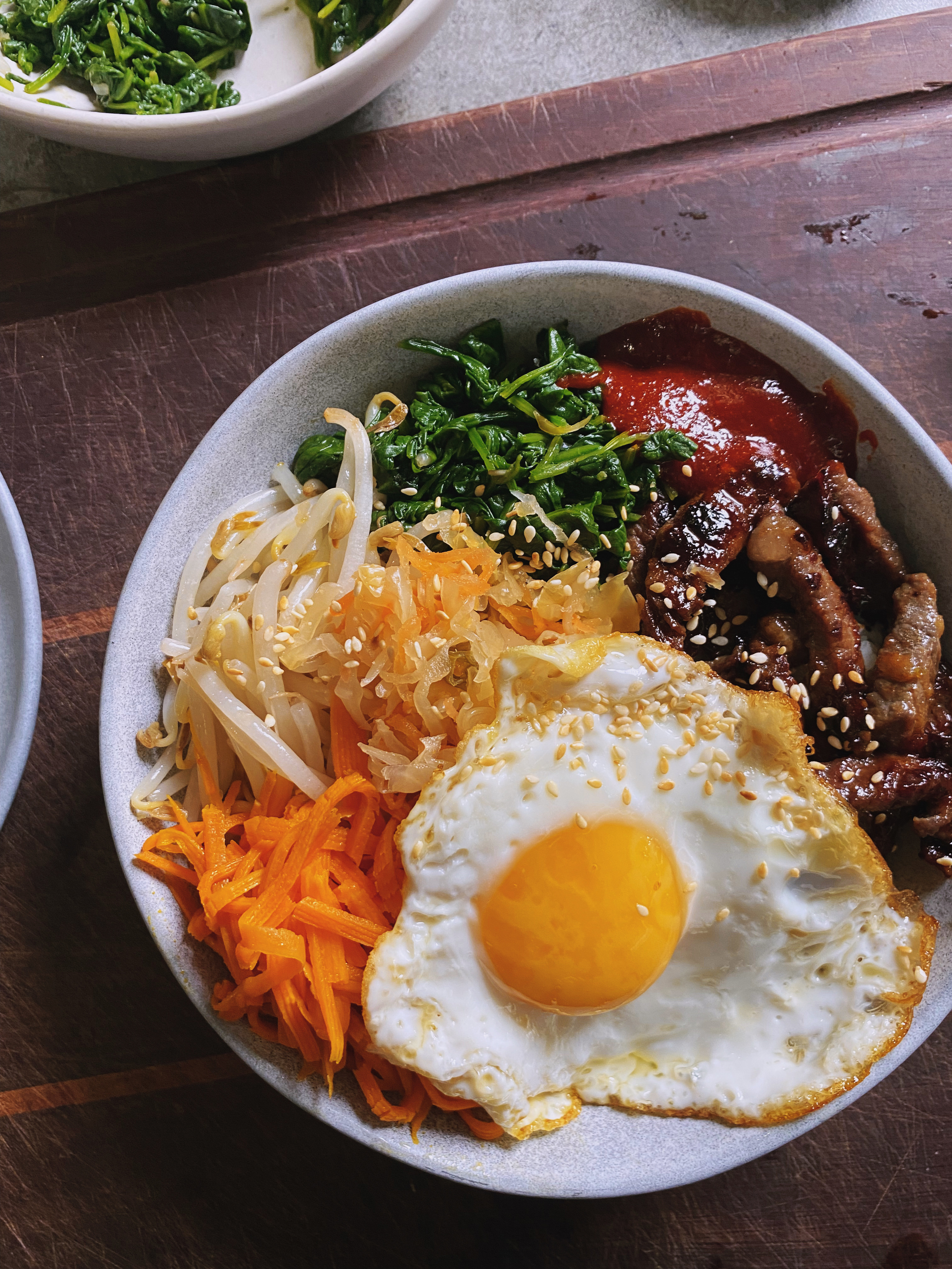 A bowl of beef bibimbap, with veggies and an egg