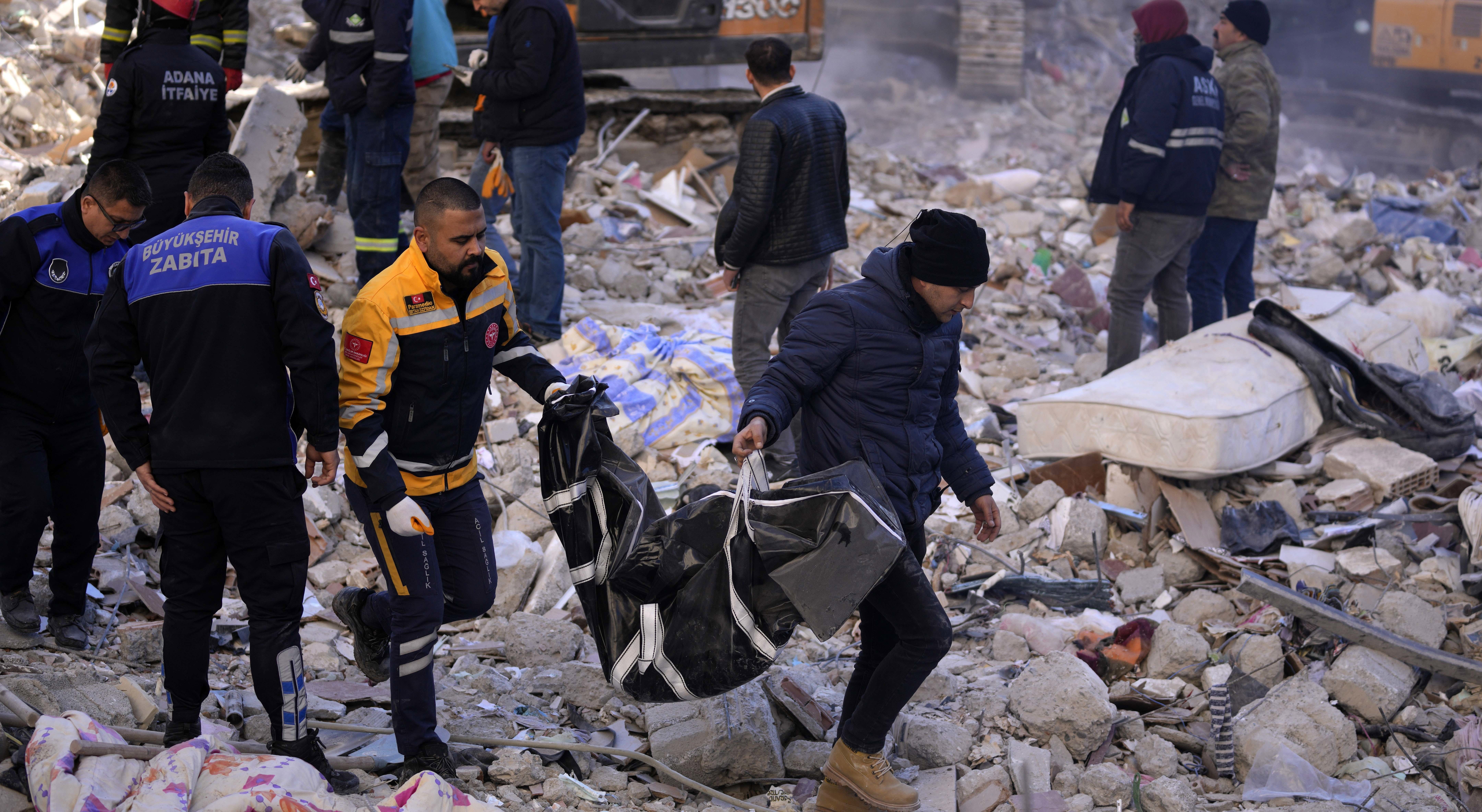 Two men carry a body from a destroyed building in Adana, southern Turkey.