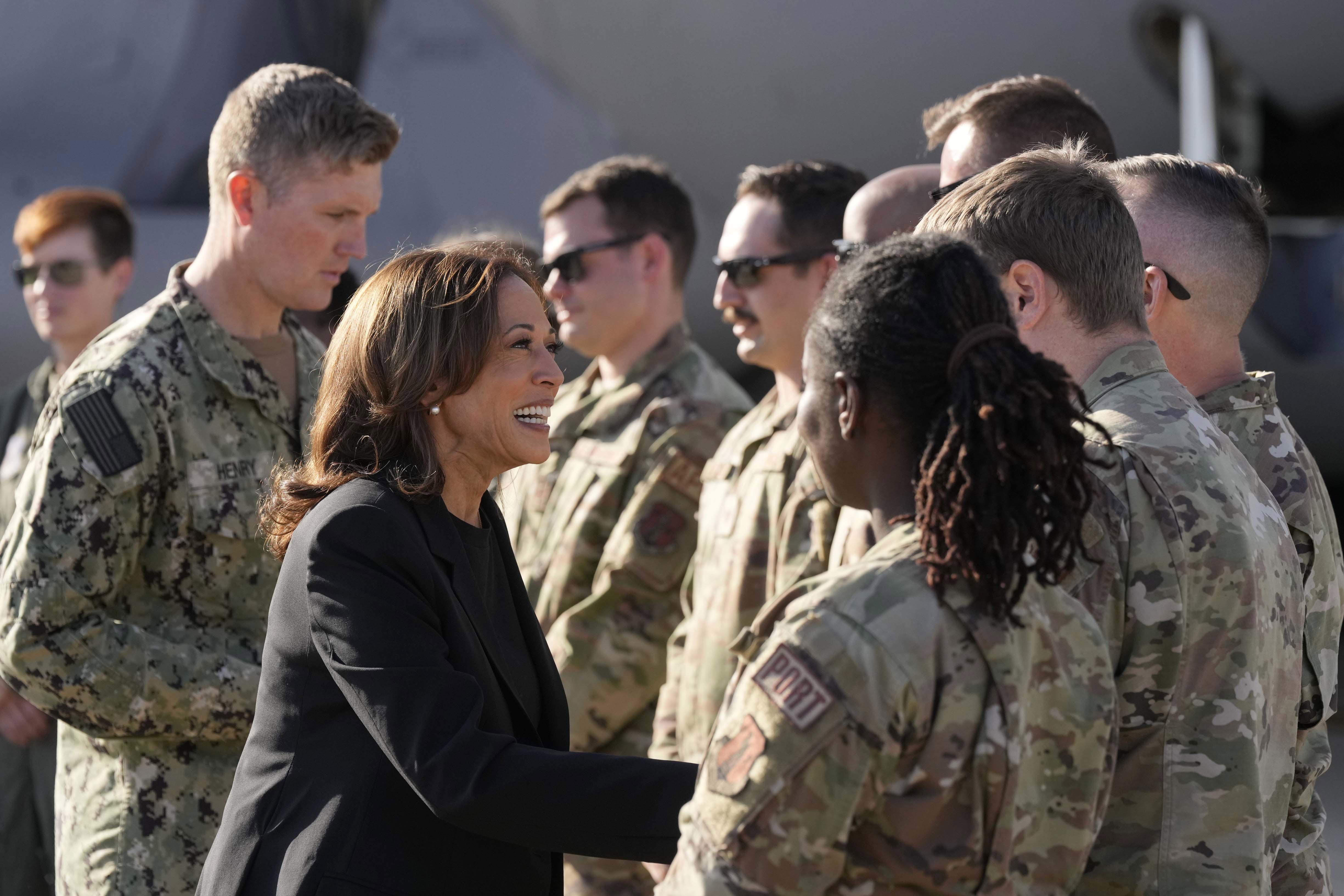 La vicepresidenta candidata demócrata a la presidencia, Kamala Harris, saluda a miembros del ejército cerca de un avión de carga C-17 después de recibir información sobre los daños causados ​​por el huracán Helene.