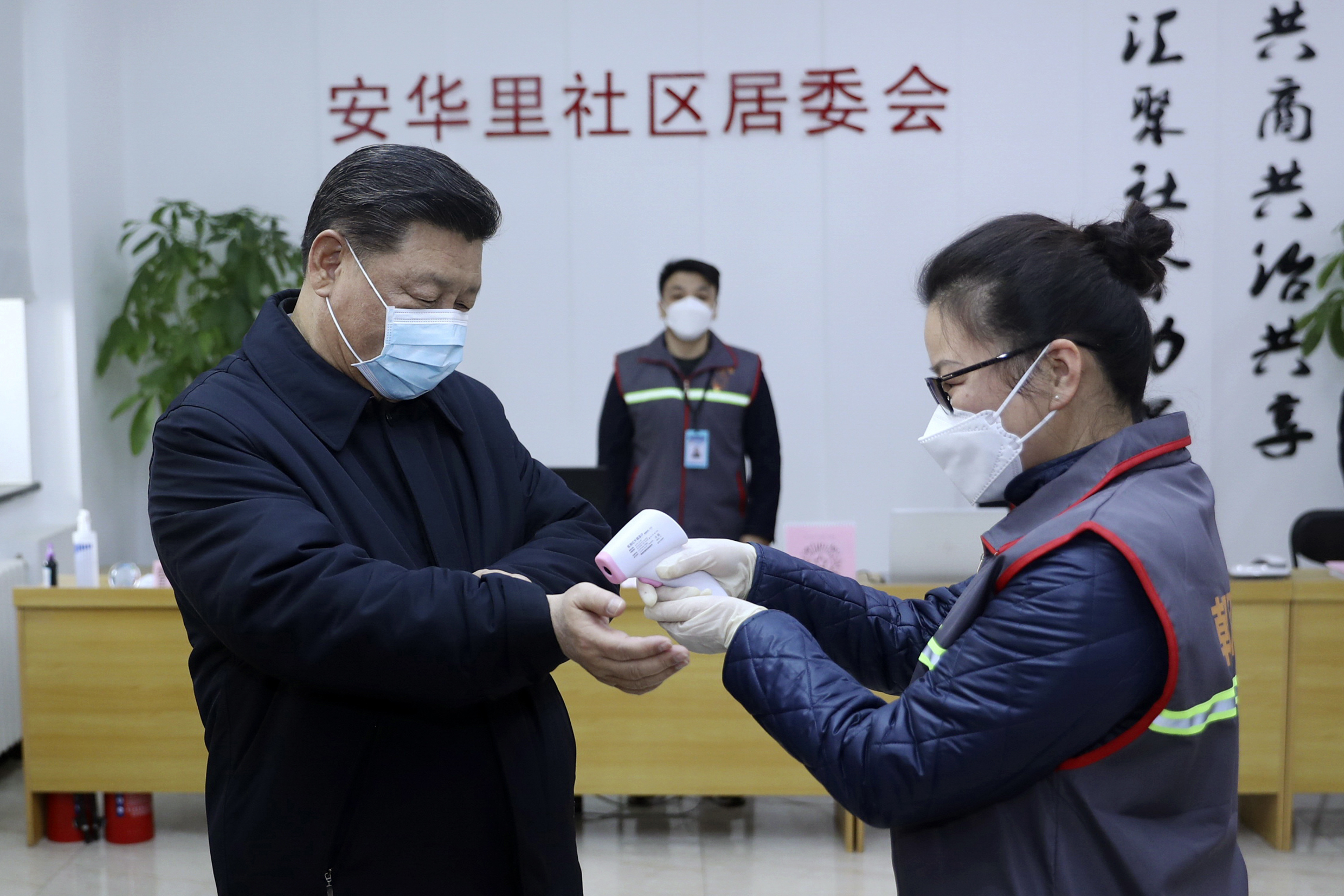 Chinese President Xi Jinping, left, wearing a protective face mask receives a temperature check.
