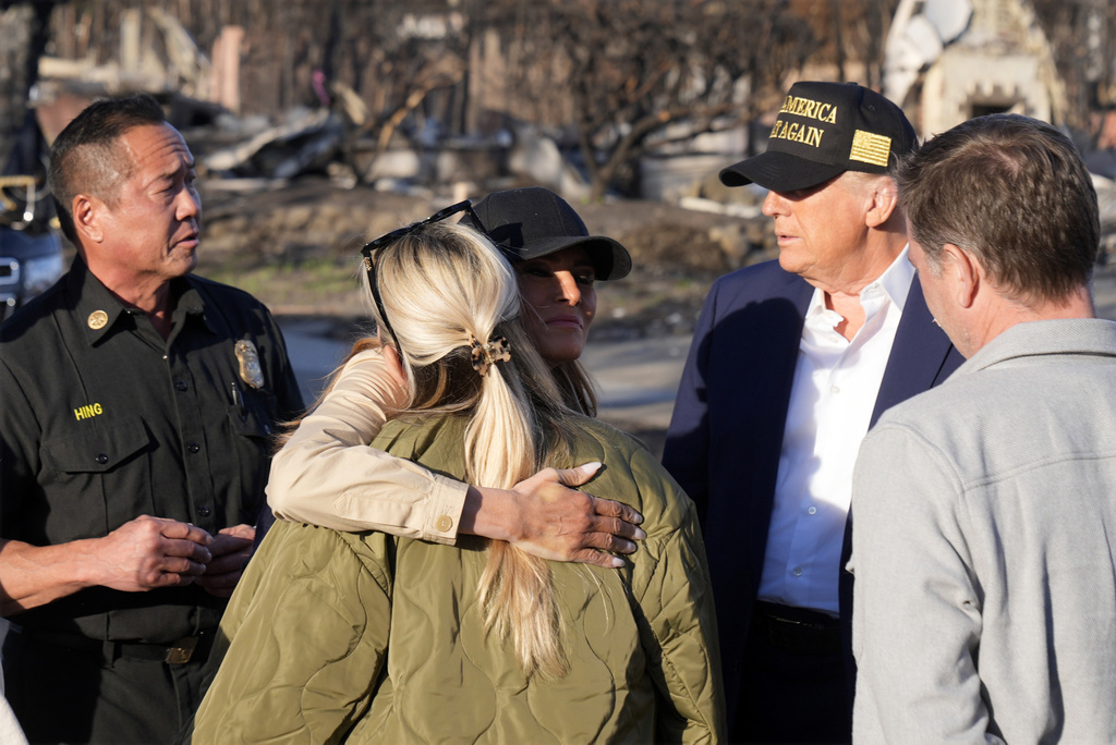 El presidente Donald Trump observa cómo la primera dama Melania Trump abraza a un residente, mientras recorren el vecindario de Pacific Palisades afectado por los recientes incendios forestales en Los Ángeles, el viernes 24 de enero de 2025. (Photo/Mark Schiefelbein)