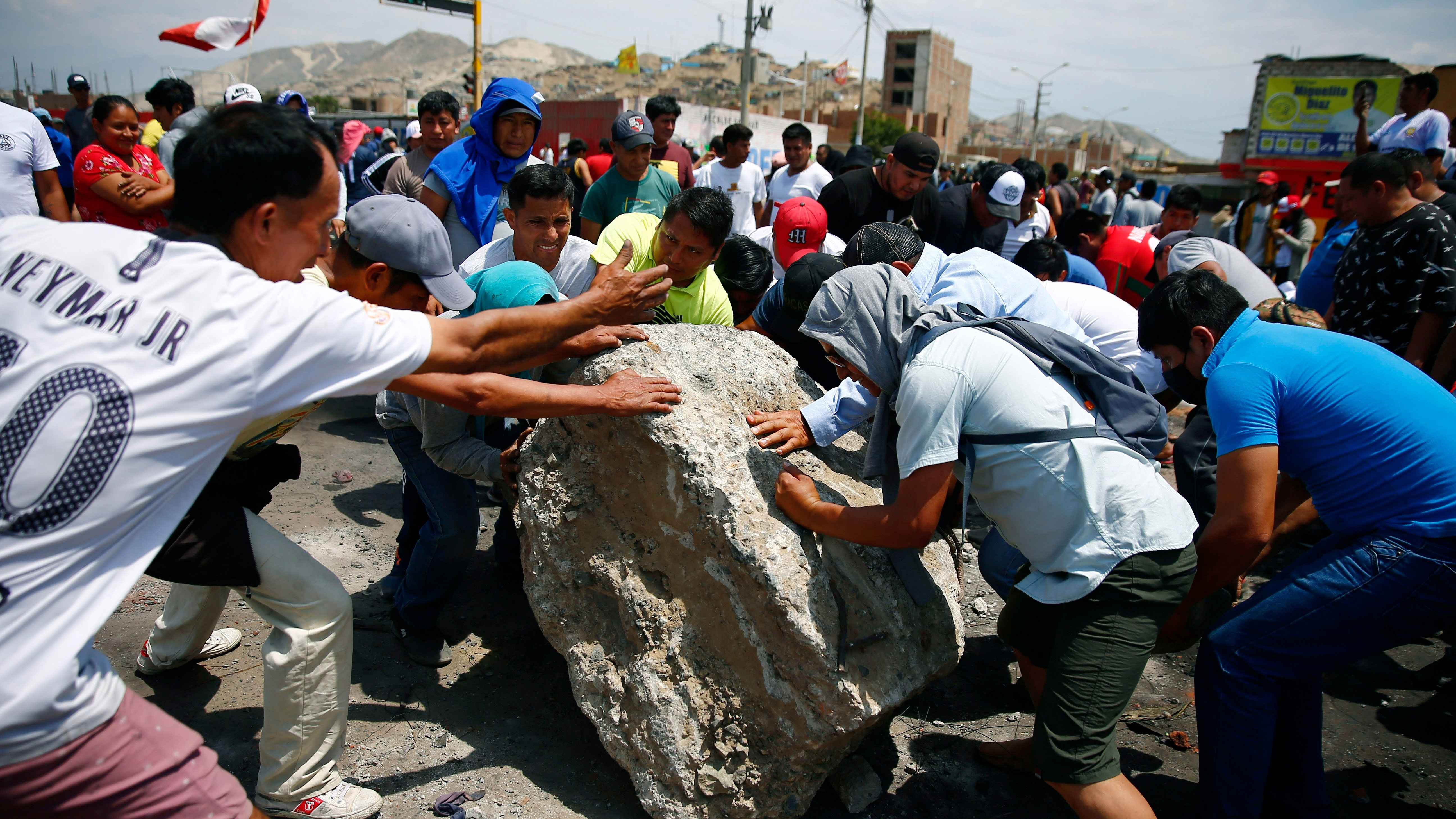 Supporters of ousted Peruvian President Pedro Castillo work together to roll a boulder onto the Pan-American North Highway