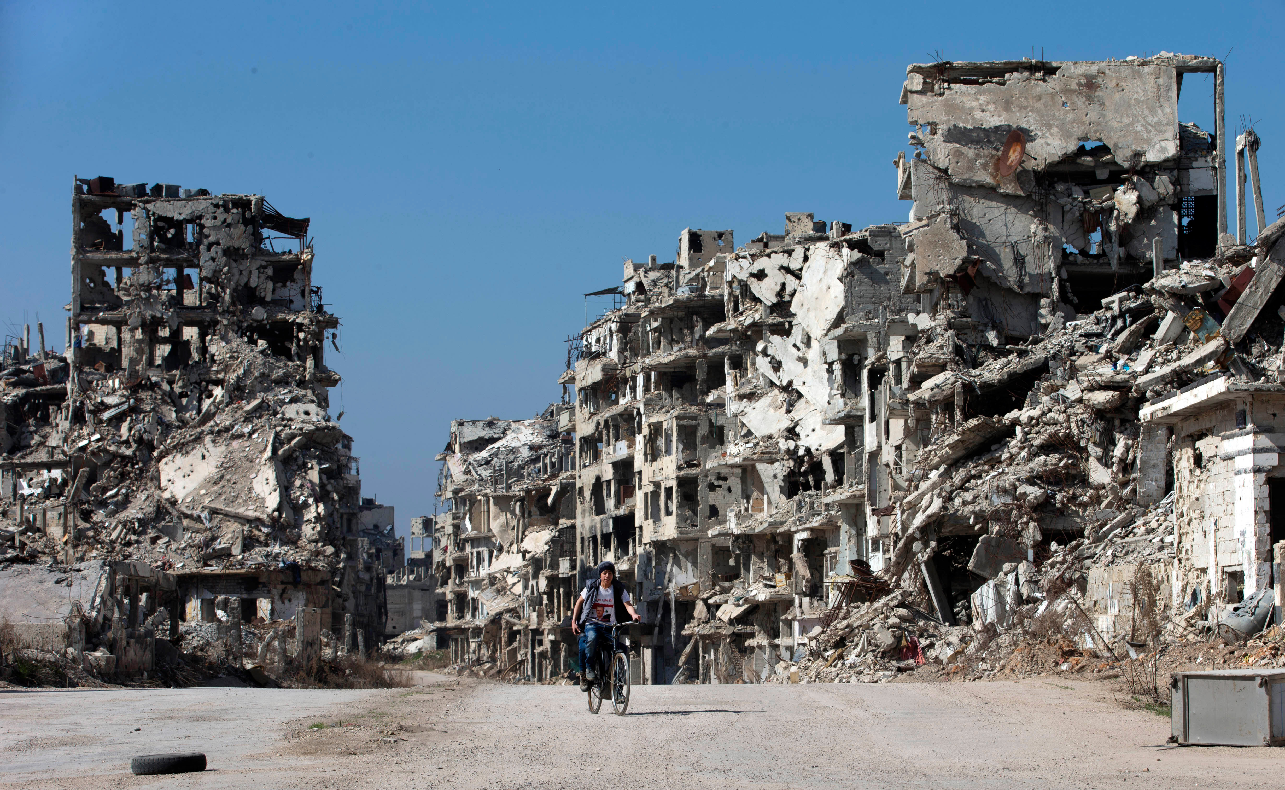 A Syrian boy rides a bicycle through a devastated part of the old city of Homs, Syria.
