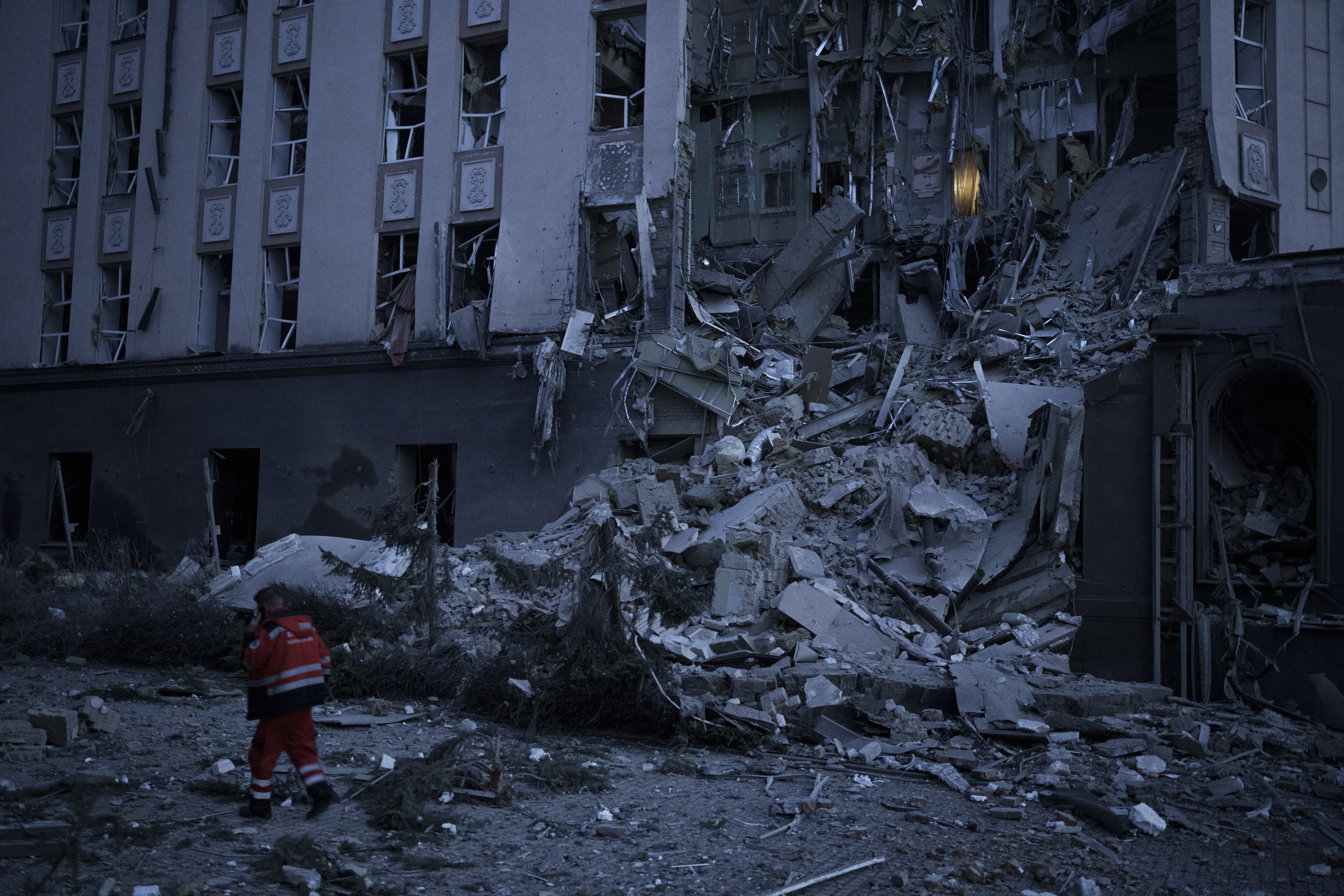 An emergency worker walks in front of a damaged hotel following a Russian attack in Kyiv, Ukraine, Saturday, Dec. 31, 2022.