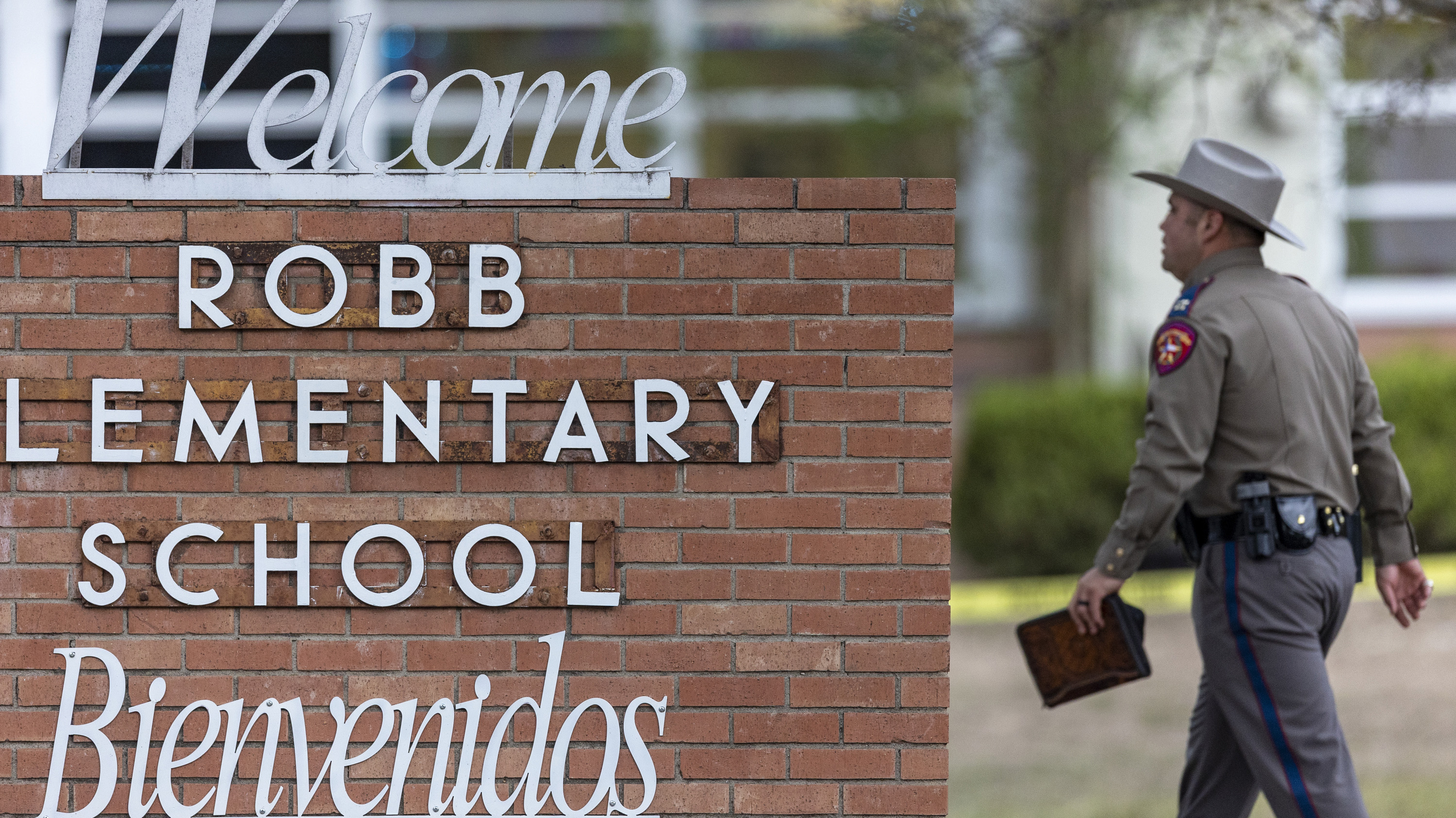 Un policía estatal pasa junto al letrero de la Escuela Primaria Robb en Uvalde, Texas, luego de un tiroteo mortal en la escuela.