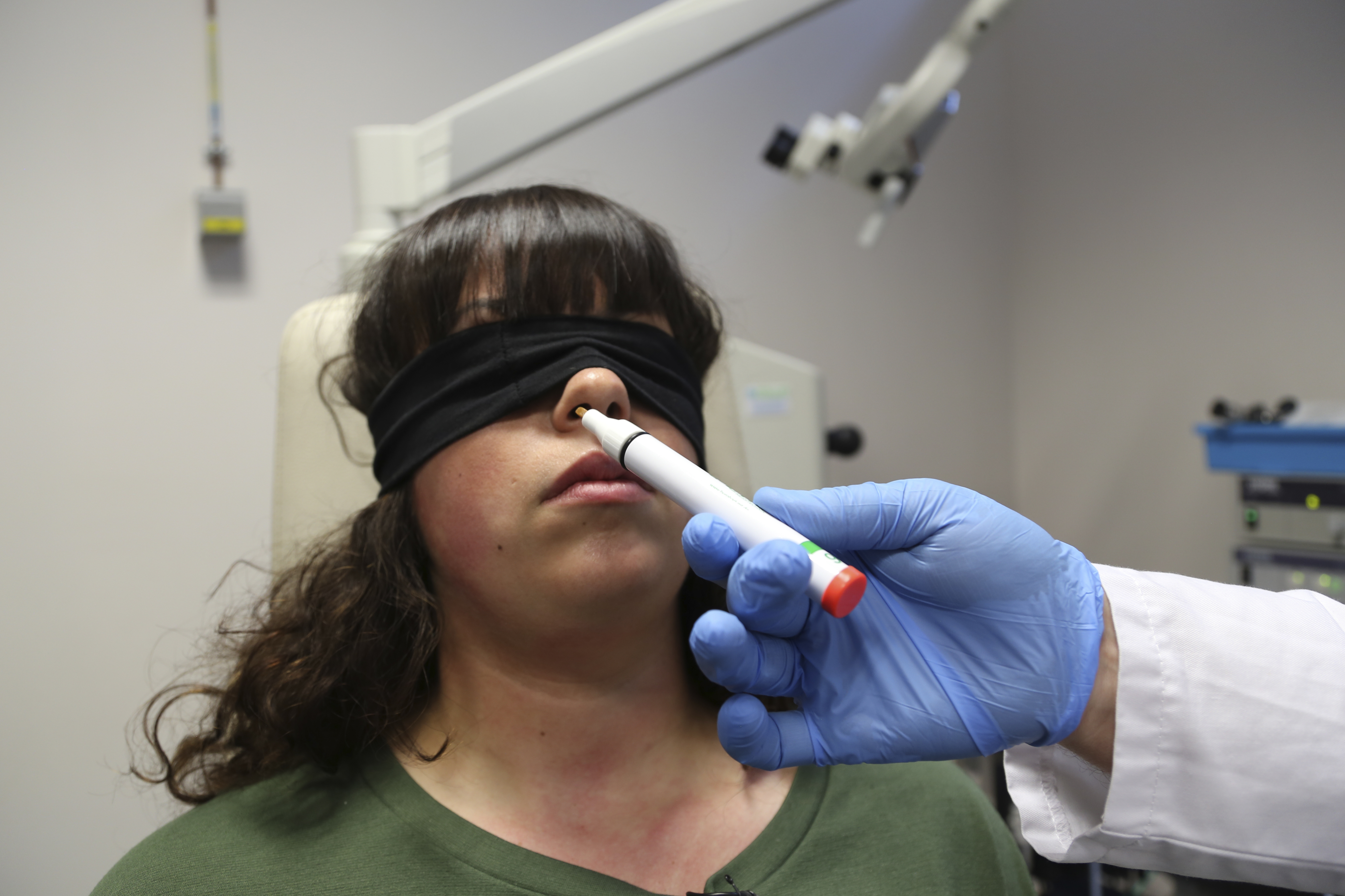 The hand of Dr. Clair Vandersteen wafts a tube of odors under the nose of a blindfolded patient, Gabriella Forgione. 