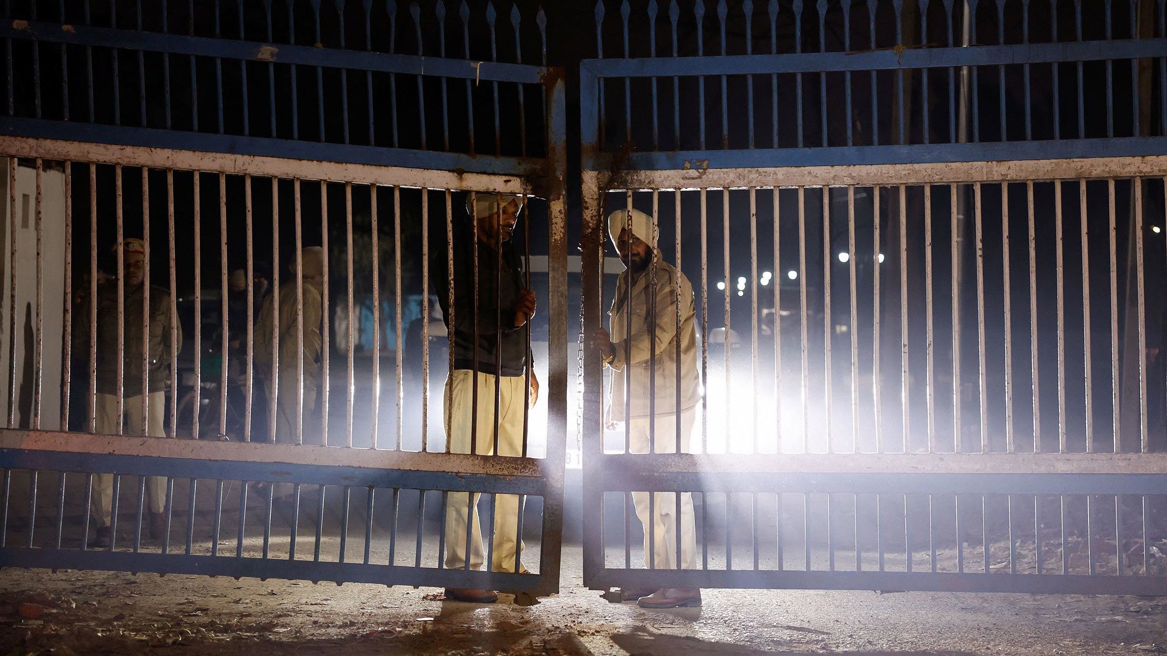 La policía está guardando en la puerta cuando los vehículos que transportan a los inmigrantes deportados abandonan el aeropuerto de Amritsar, India.