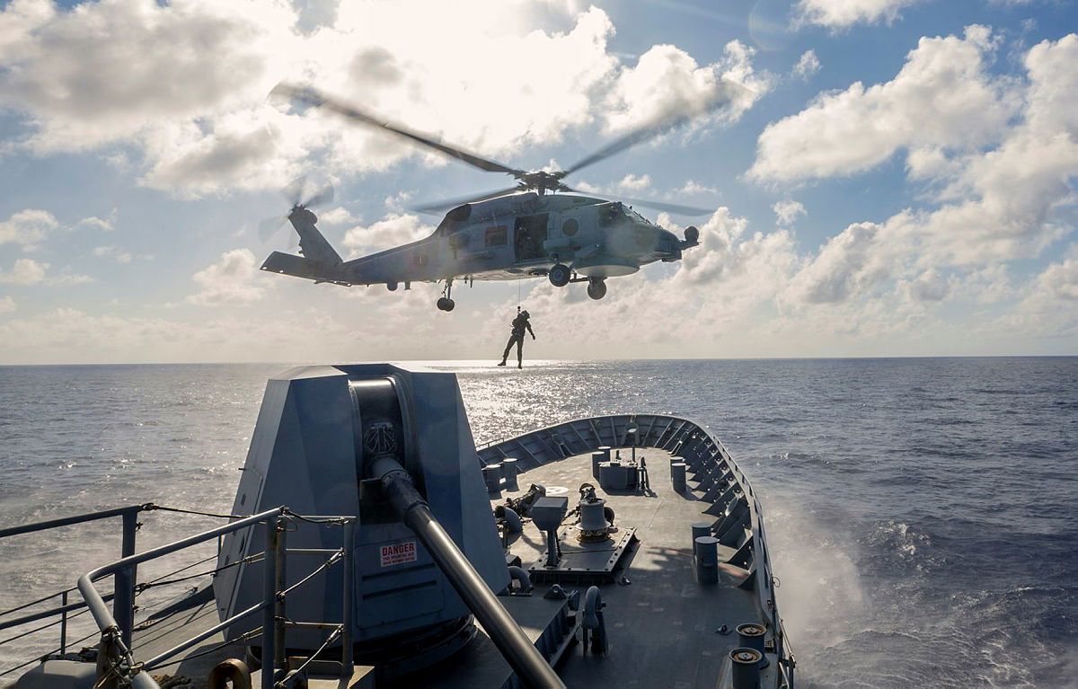 An MH-60R Seahawk from HMAS Toowoomba conducts a PAX transfer from the forecastle of the ship while the ship sails through the Philippines Sea.