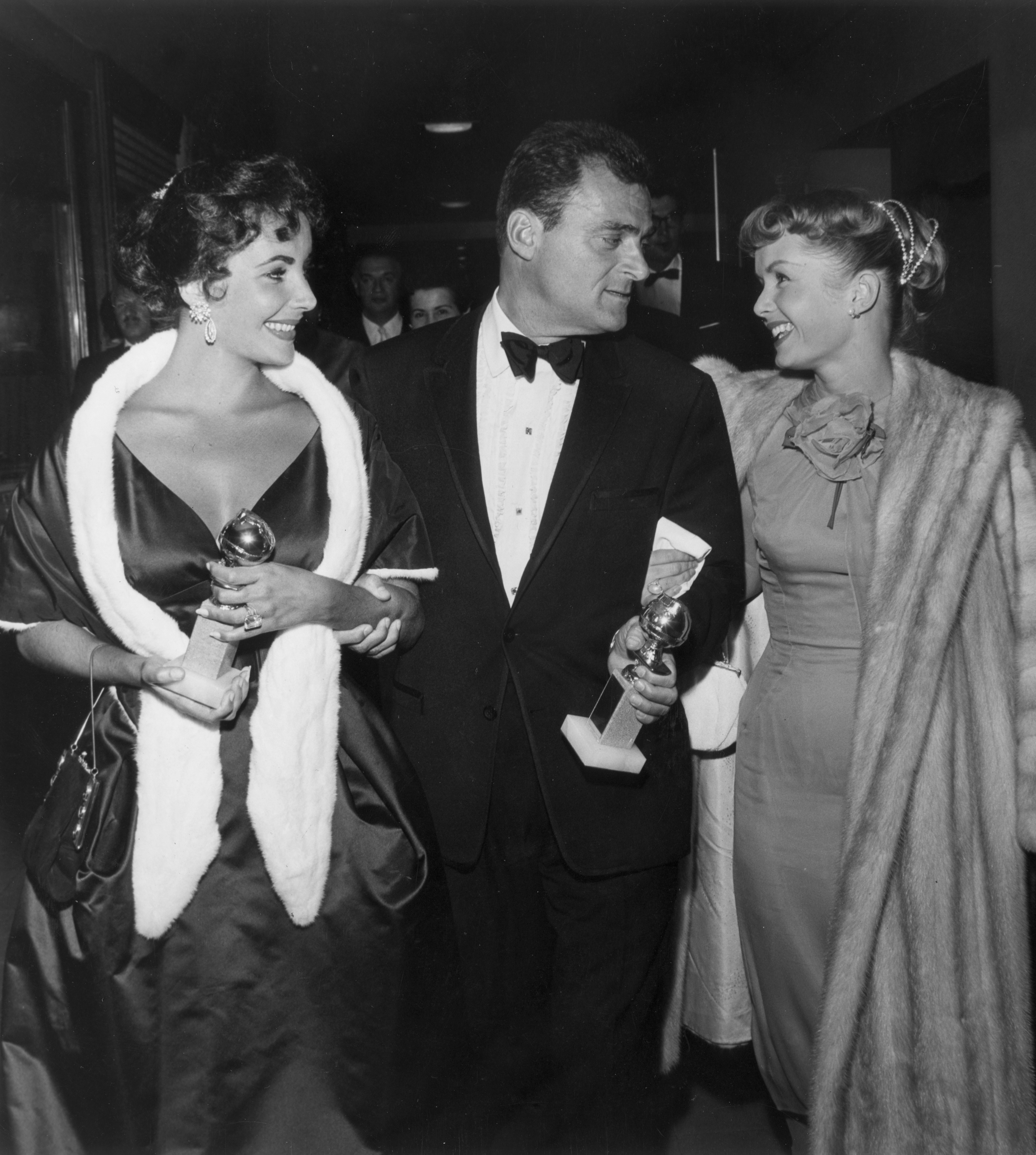 Elizabeth Taylor and Mike Todd hold their Golden Globe awards while walking with Debbie Reynolds at the Hollywood Foreign Press Association Awards Dinner in Los Angeles on 28 February 1957