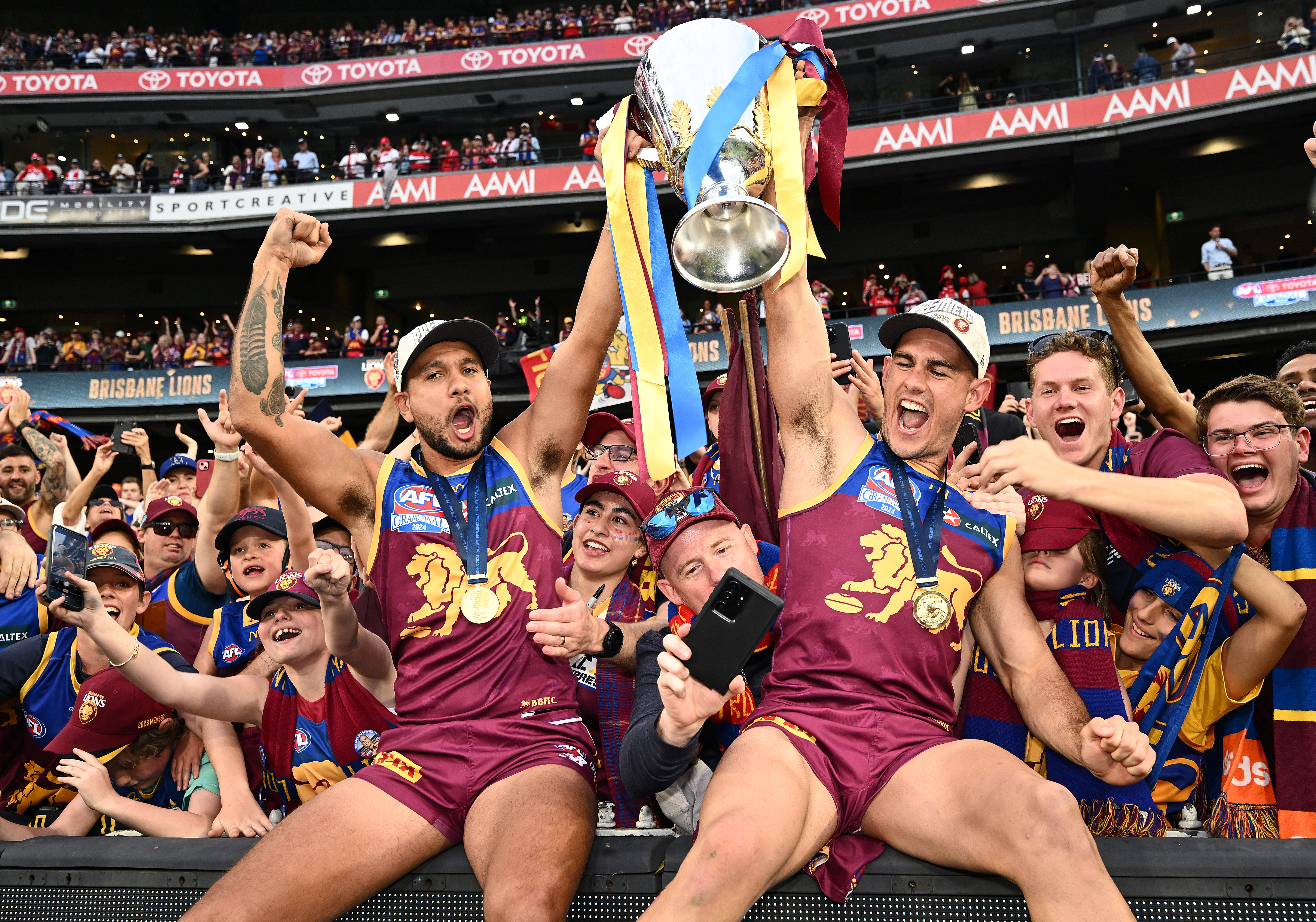 Callum Ah Chee and Brandon Starcevich of the Lions celebrate with the premiership cup.