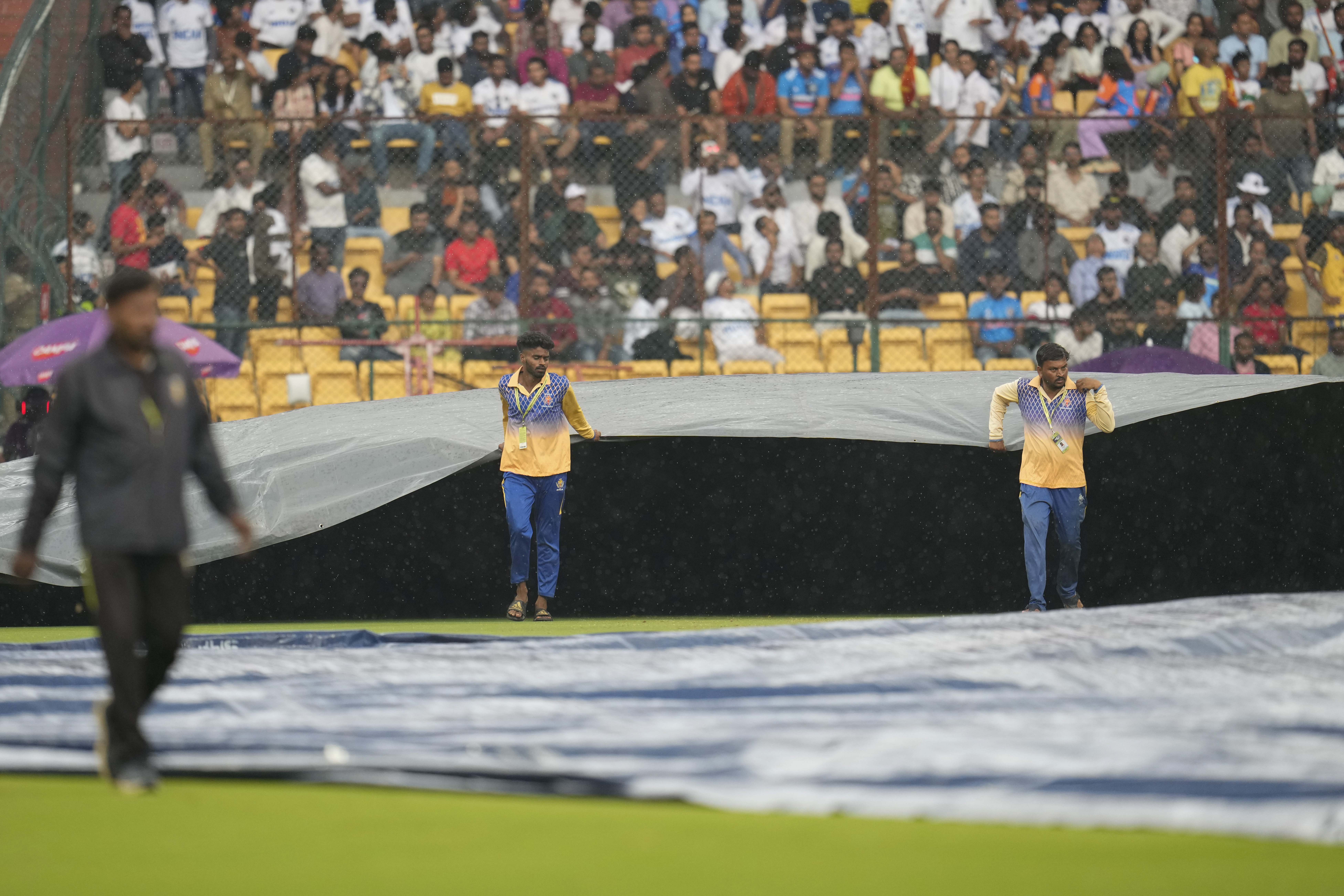 Groundsmen pull on the covers after rain stopped play on day four of the first Test match between India and New Zealand.