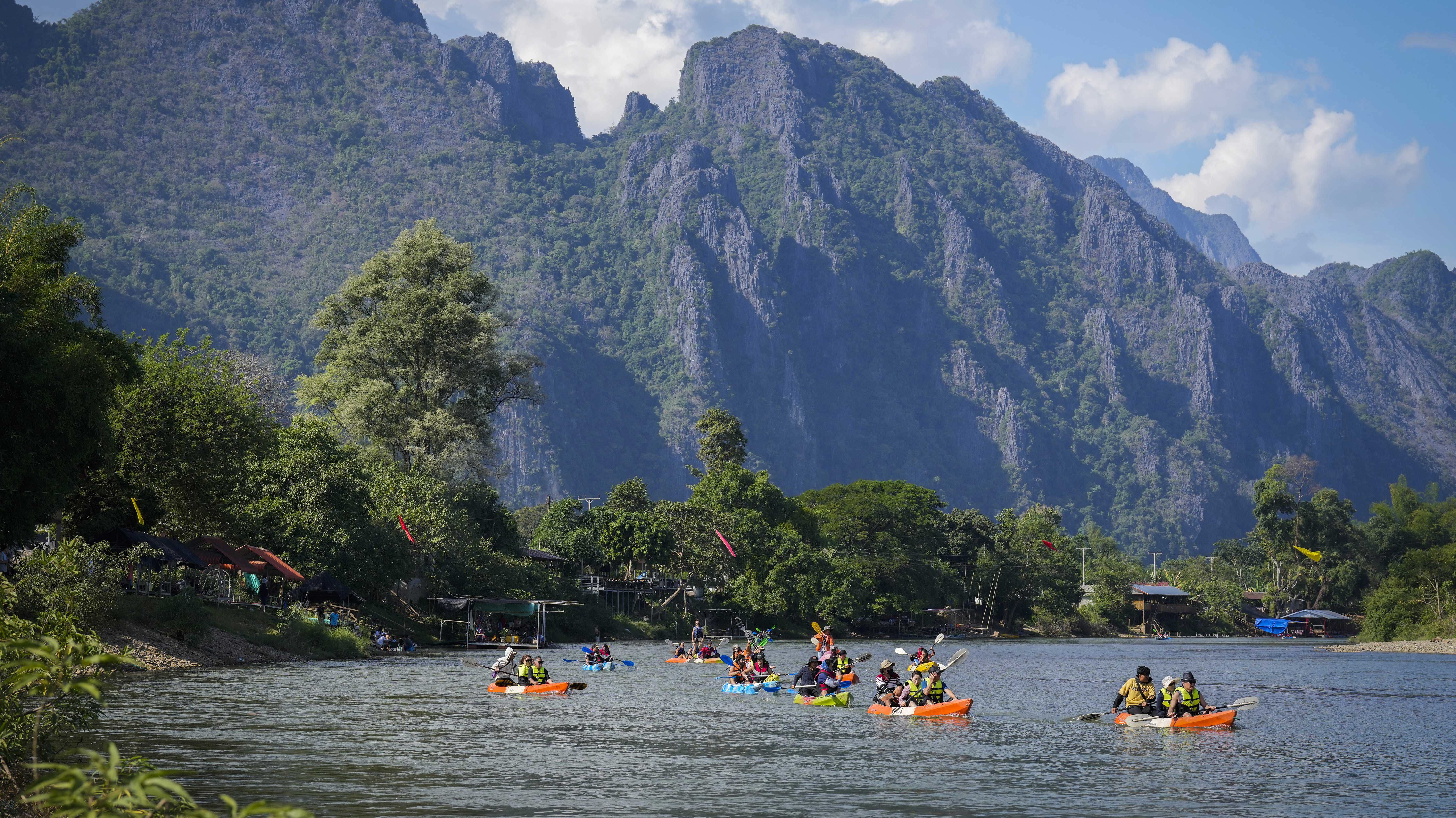 Tourists ride on kayaks in Namsong river in Vang Vieng, Laos.