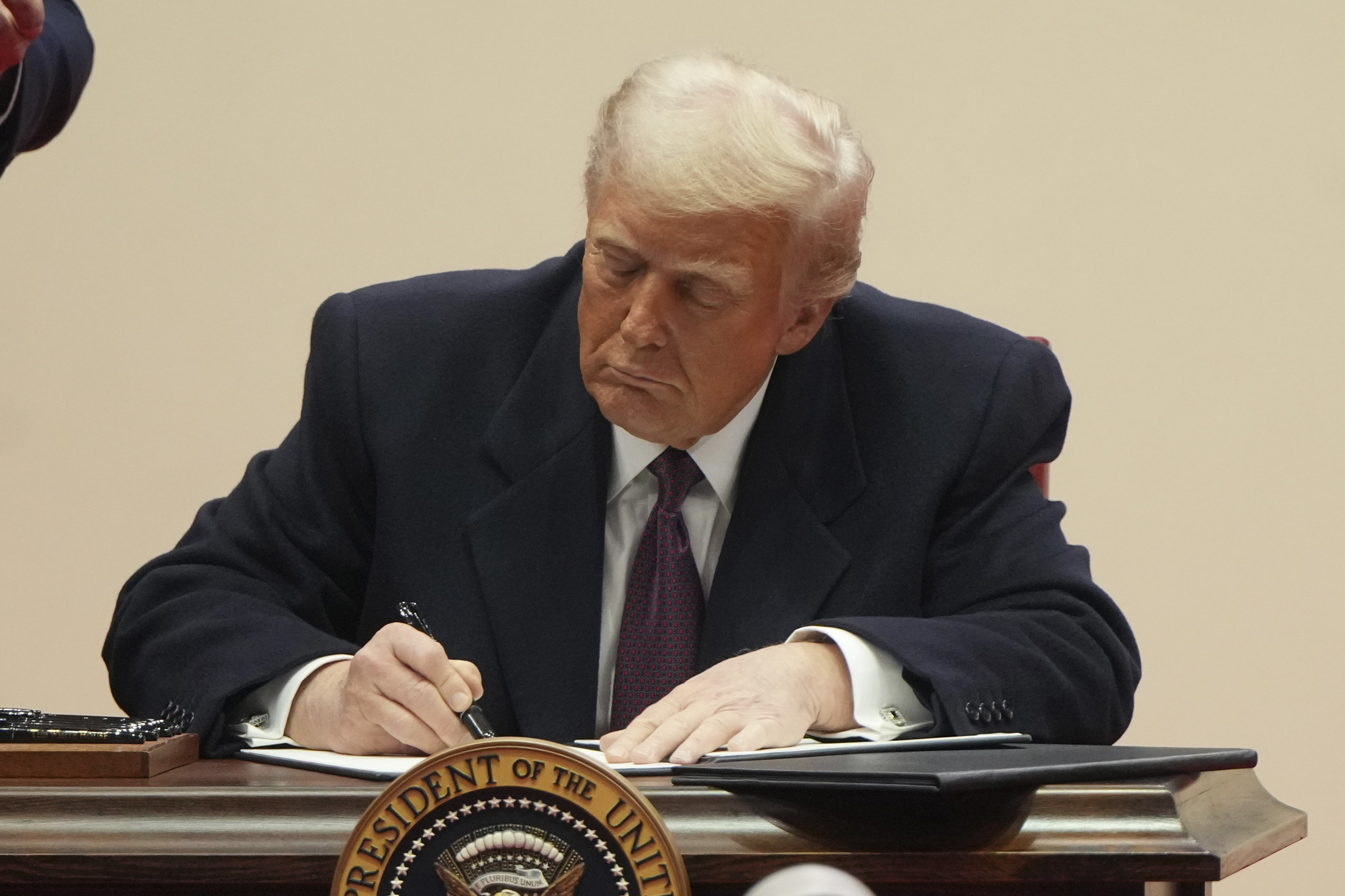 El presidente Donald Trump firma órdenes ejecutivas en un desfile de inauguración presidencial bajo techo en Washington, el lunes 20 de enero de 2025. (Foto AP/Matt Rourke