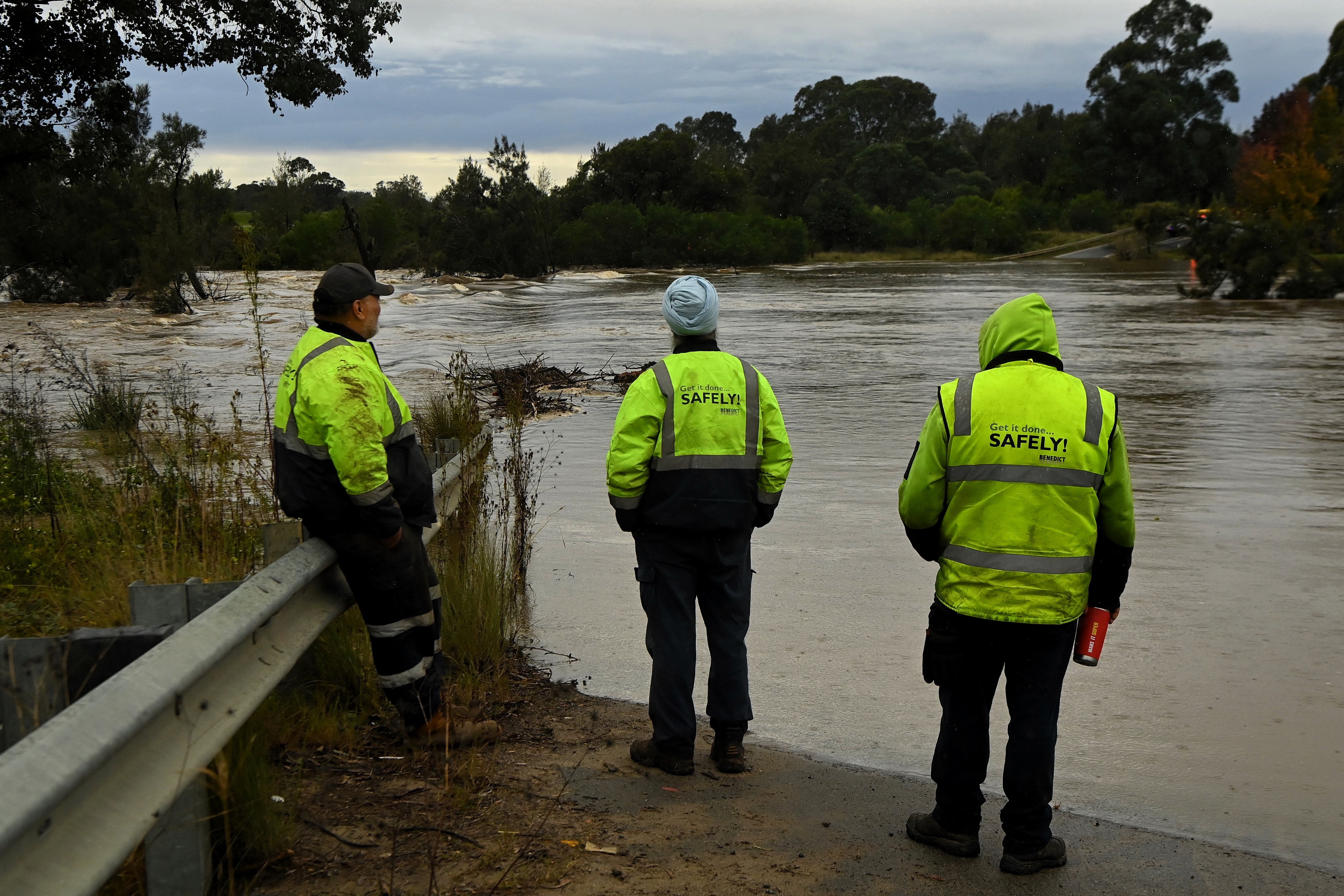 People looks at the Menangle bridge that crosses the Nepean River which is under water and where two cars were inundated by the rising flood waters . Menangle, NSW. June 7, 2024. 